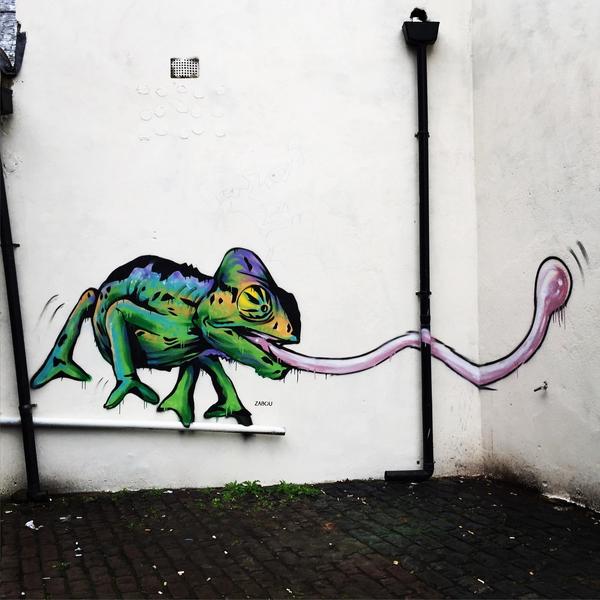 Spray painted image of a bright green chameleon sticking its tongue out