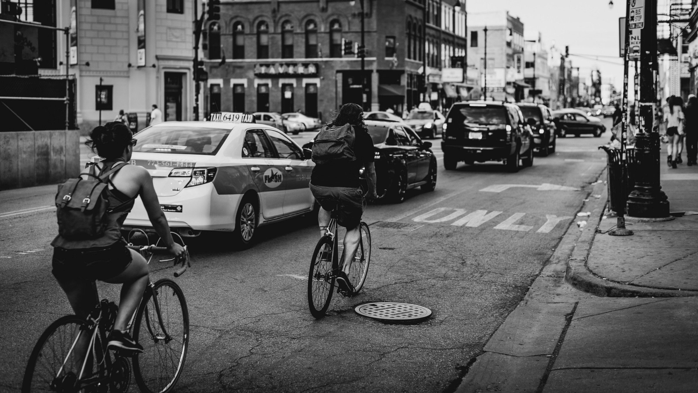 Two people cycling down busy street.