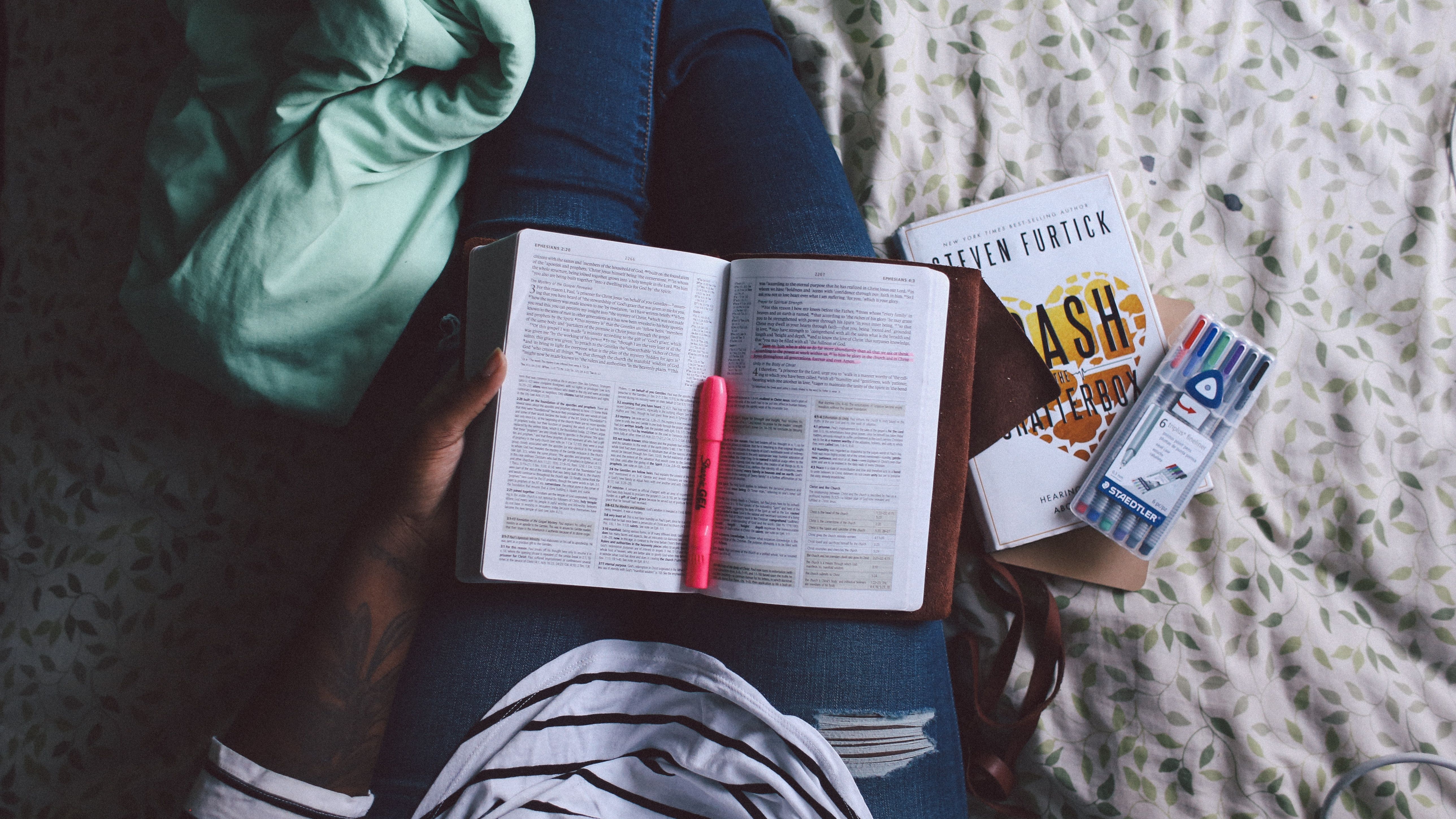 Person with an open book and highlighter on their lap
