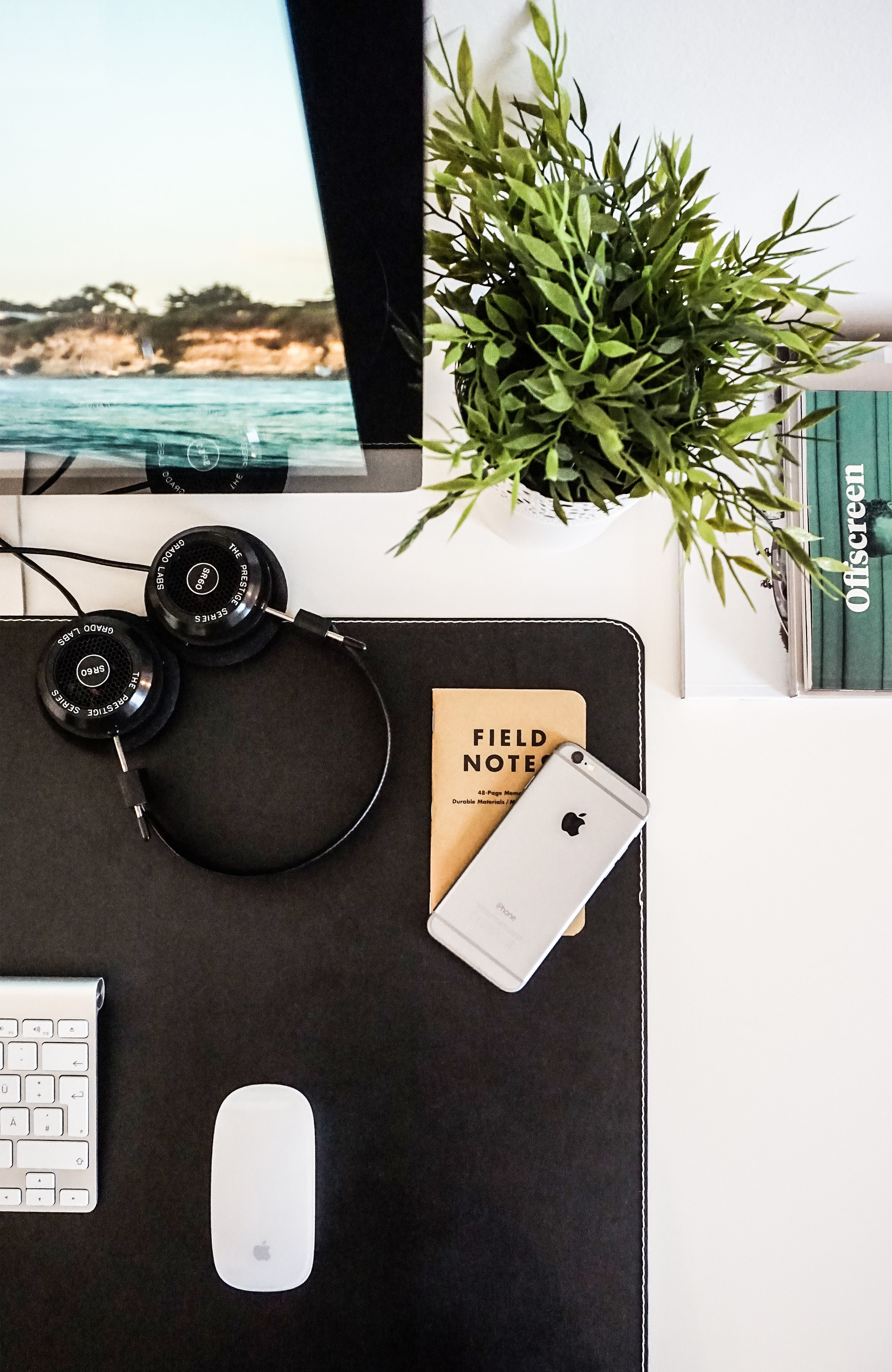 Desktop with computer, field notes, headphones and phone
