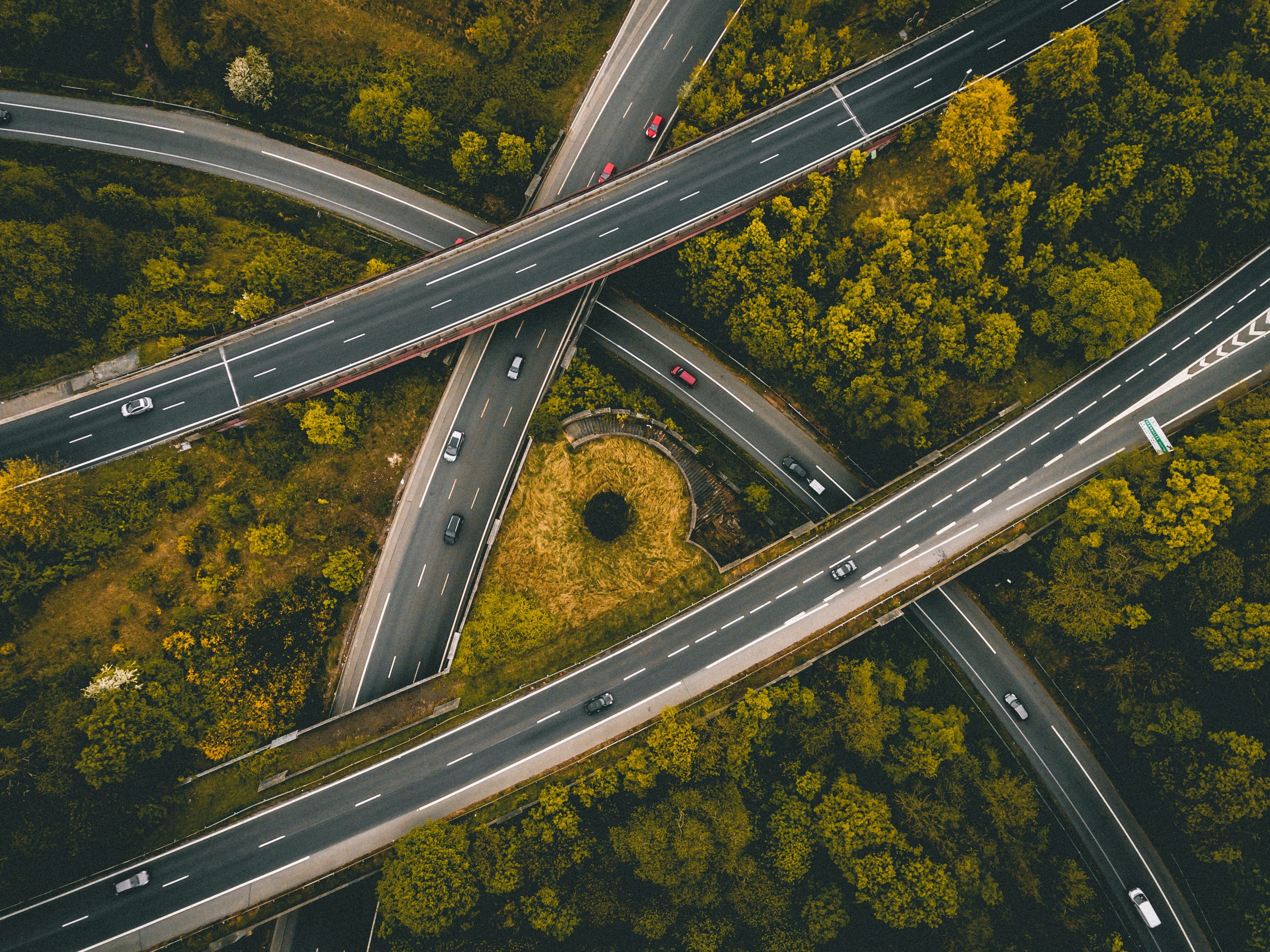 Aerial photo of intersecting freeway roads surrounded by trees.