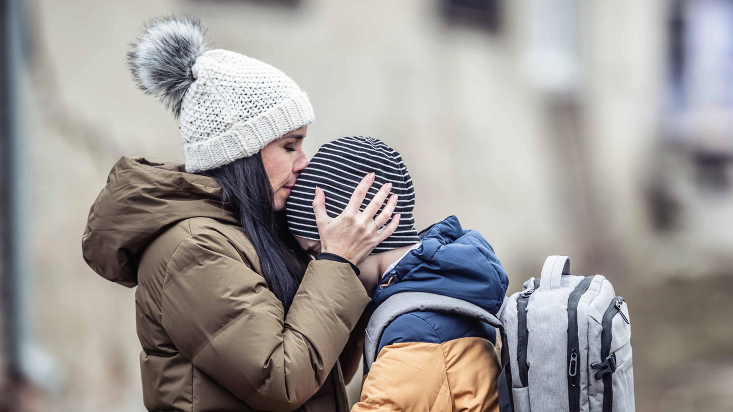 Woman kissing her son on the head in an autumn setting