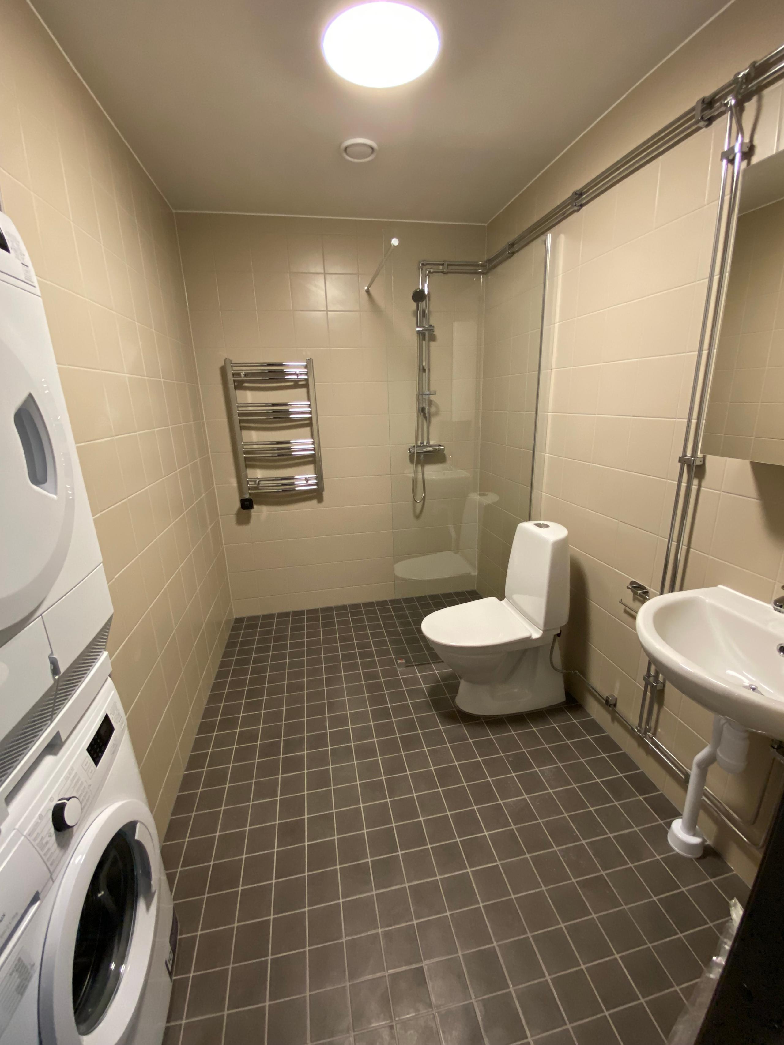 bathroom with a toilet, washbasin and washing machine/tumble dryer.