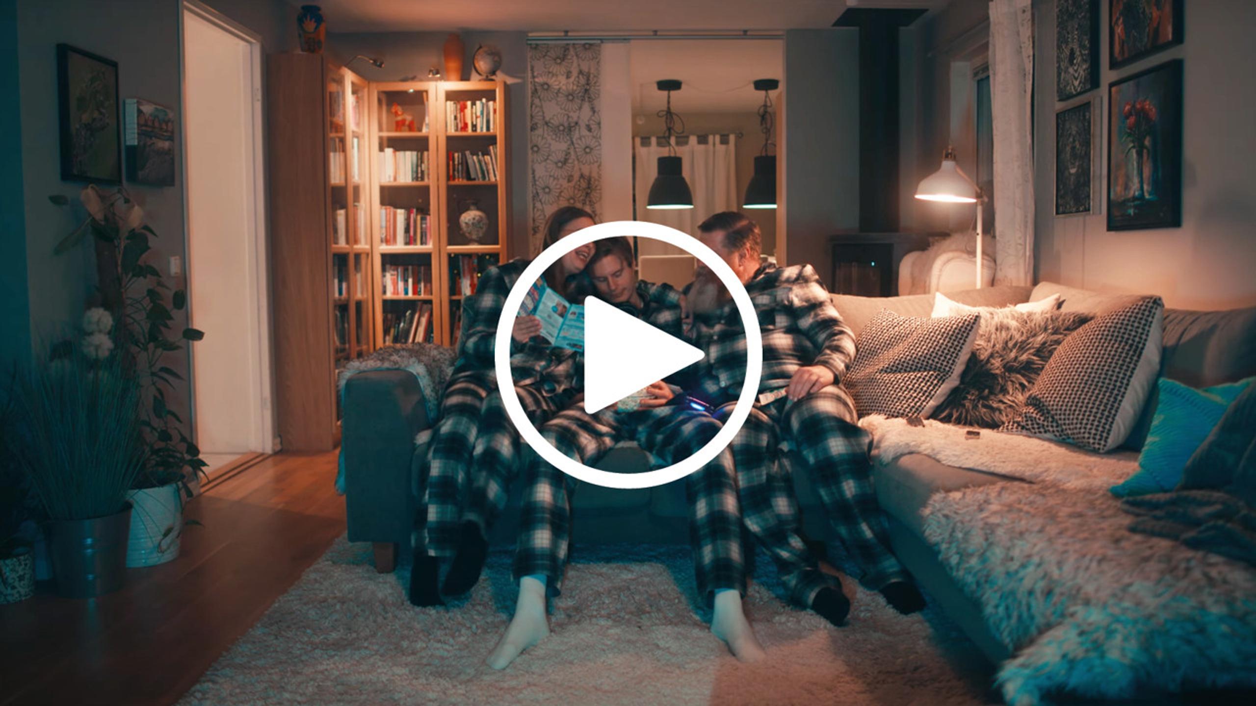 A mother and a father playing bingo on the sofa with a young adult