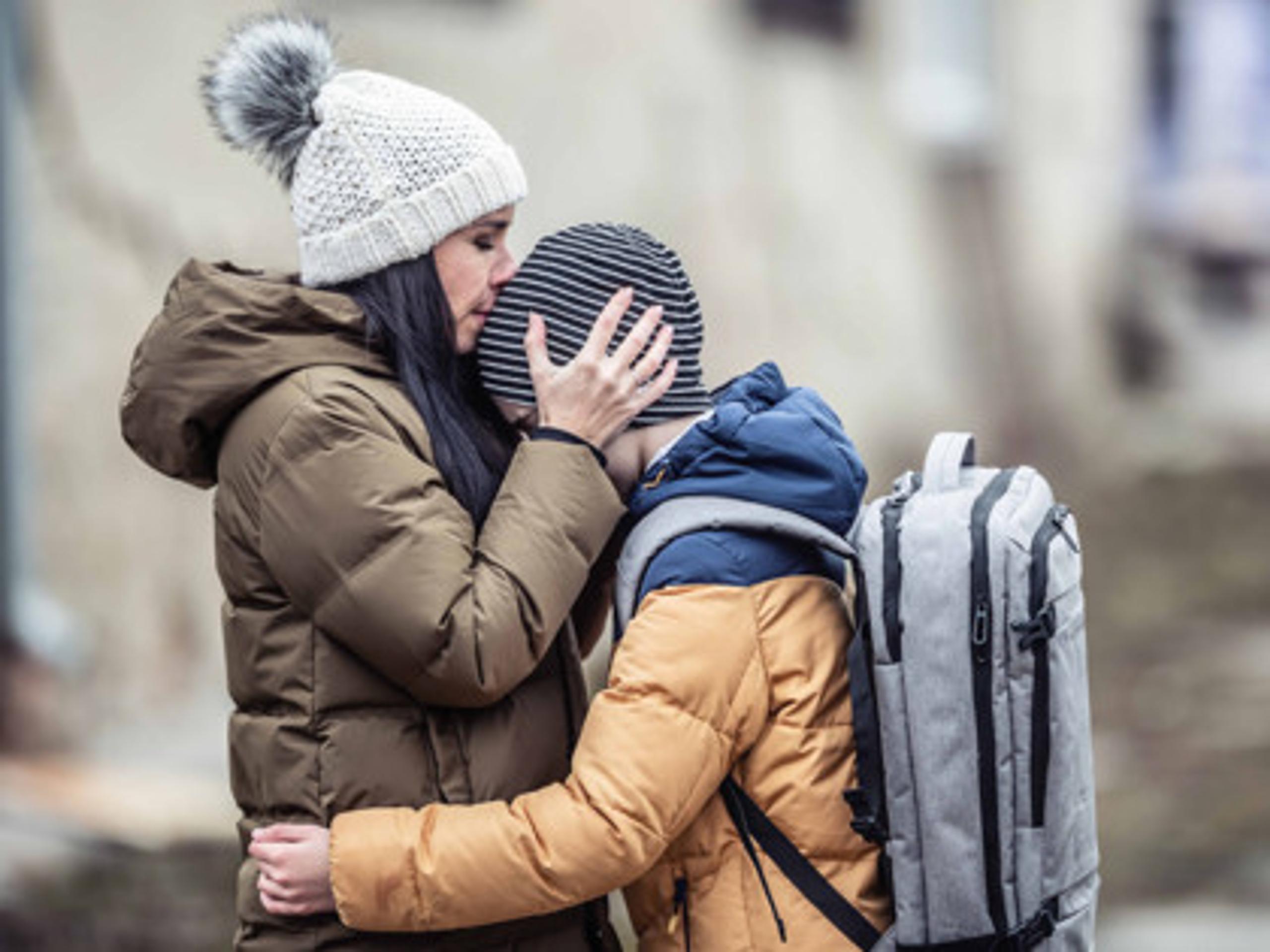 A woman kissing her son's head in an autumn setting
