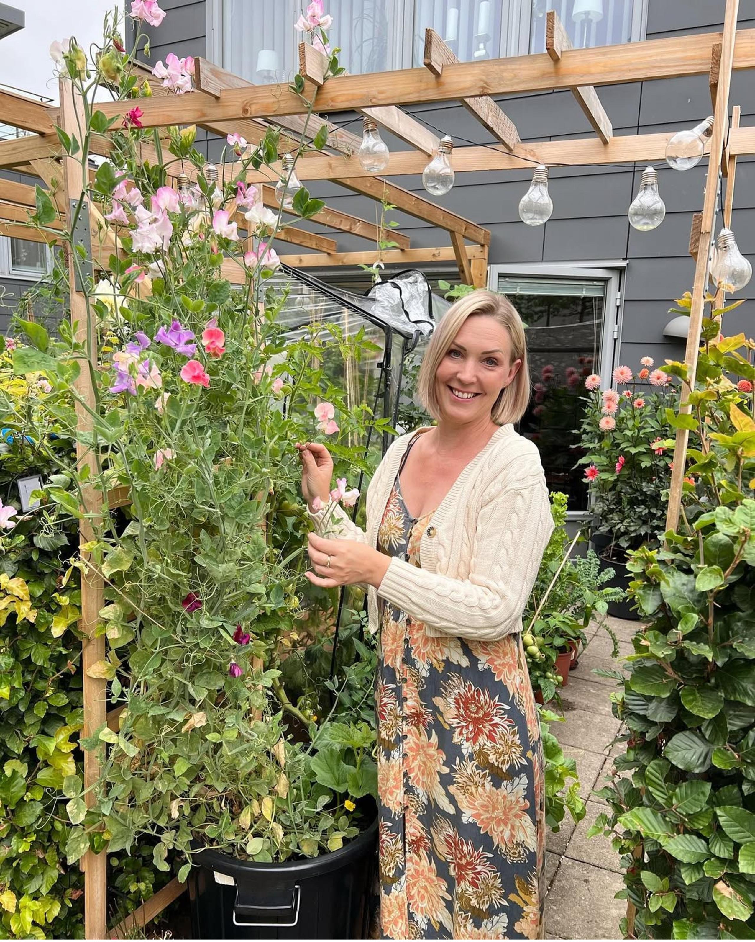 A woman stands on a patio full of flowers