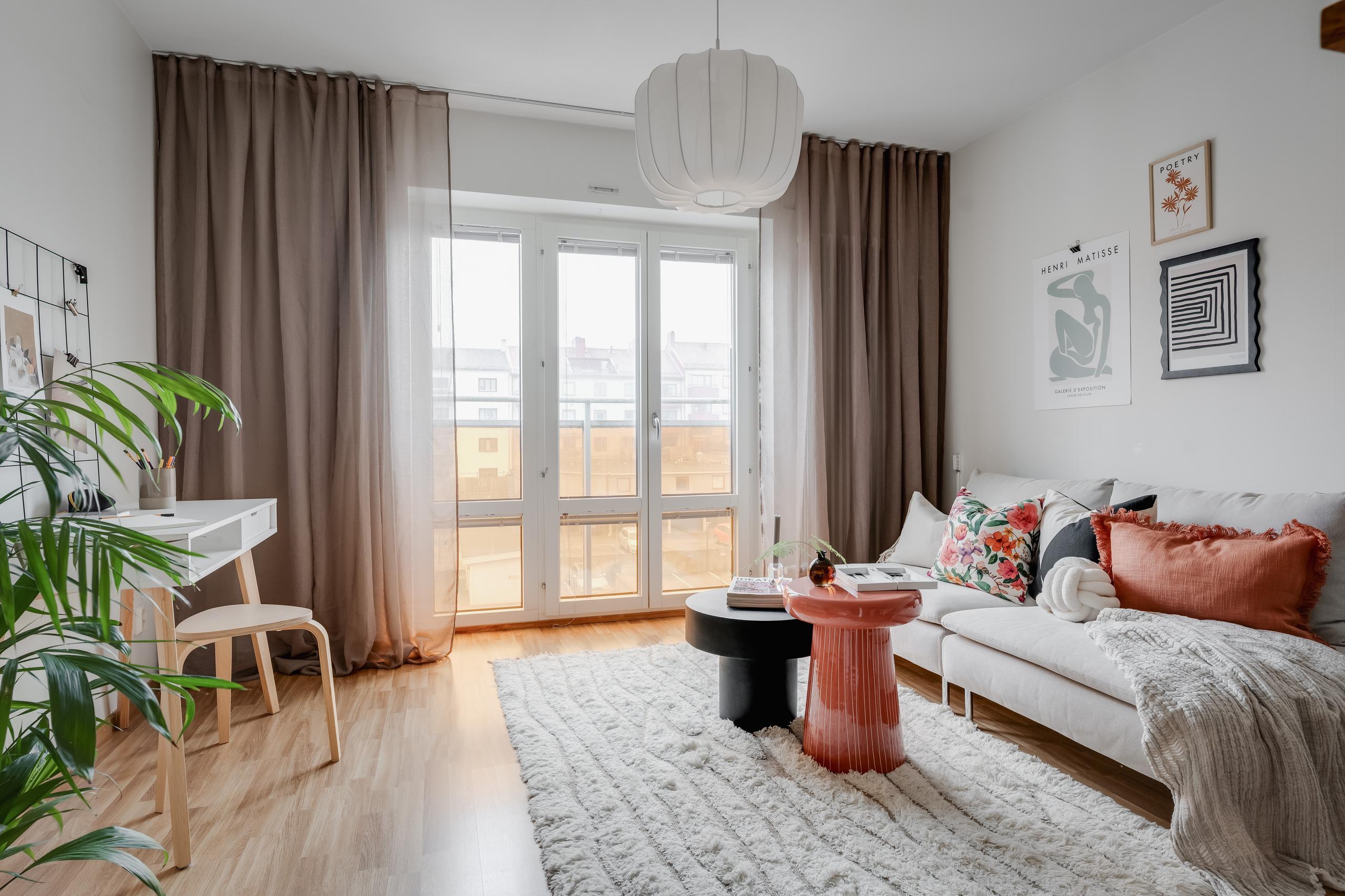 Ljust vardagsrum med soffa, soffbord och skrivbord.