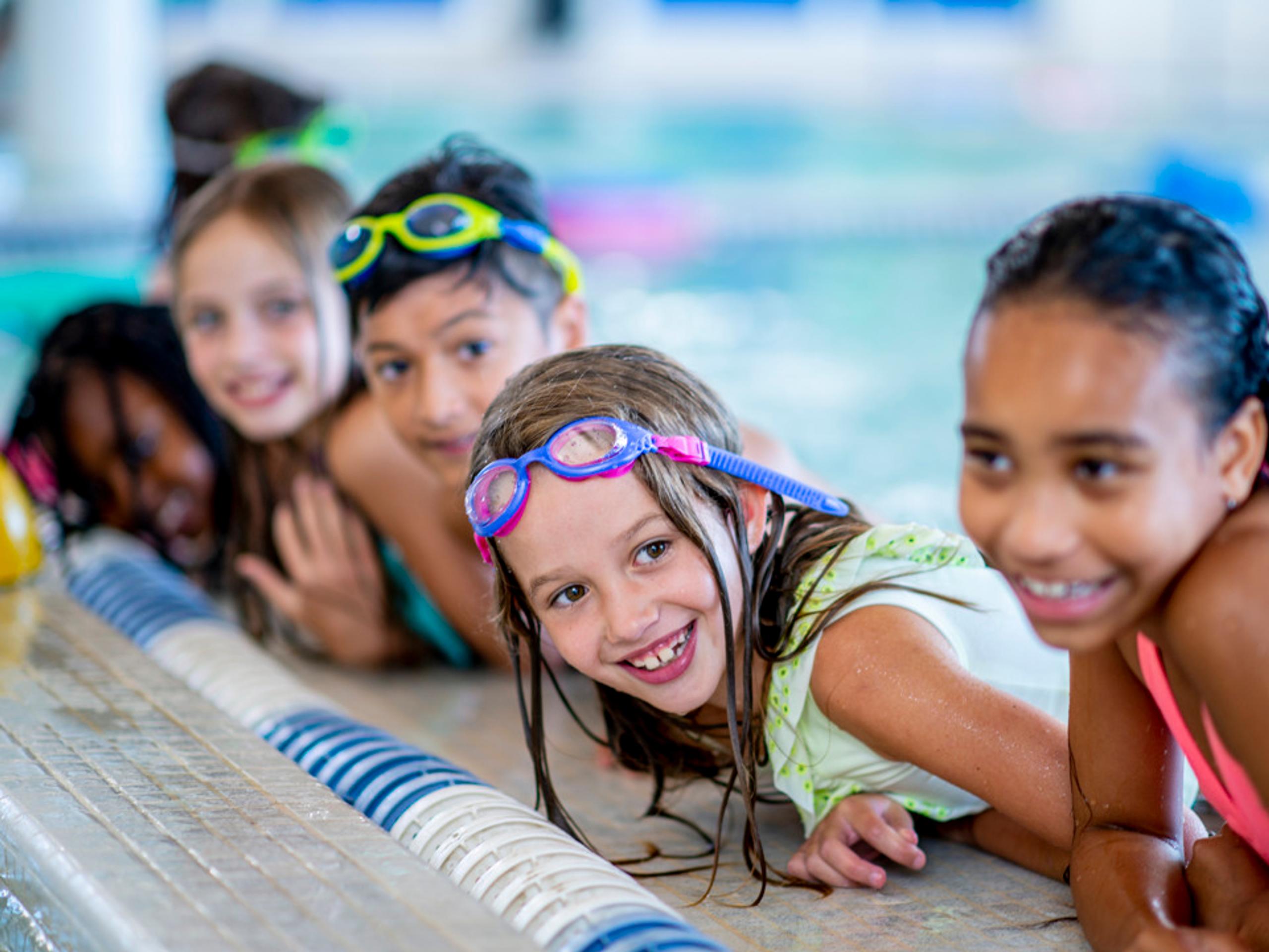 Happy children at the swimming pool learning to swim