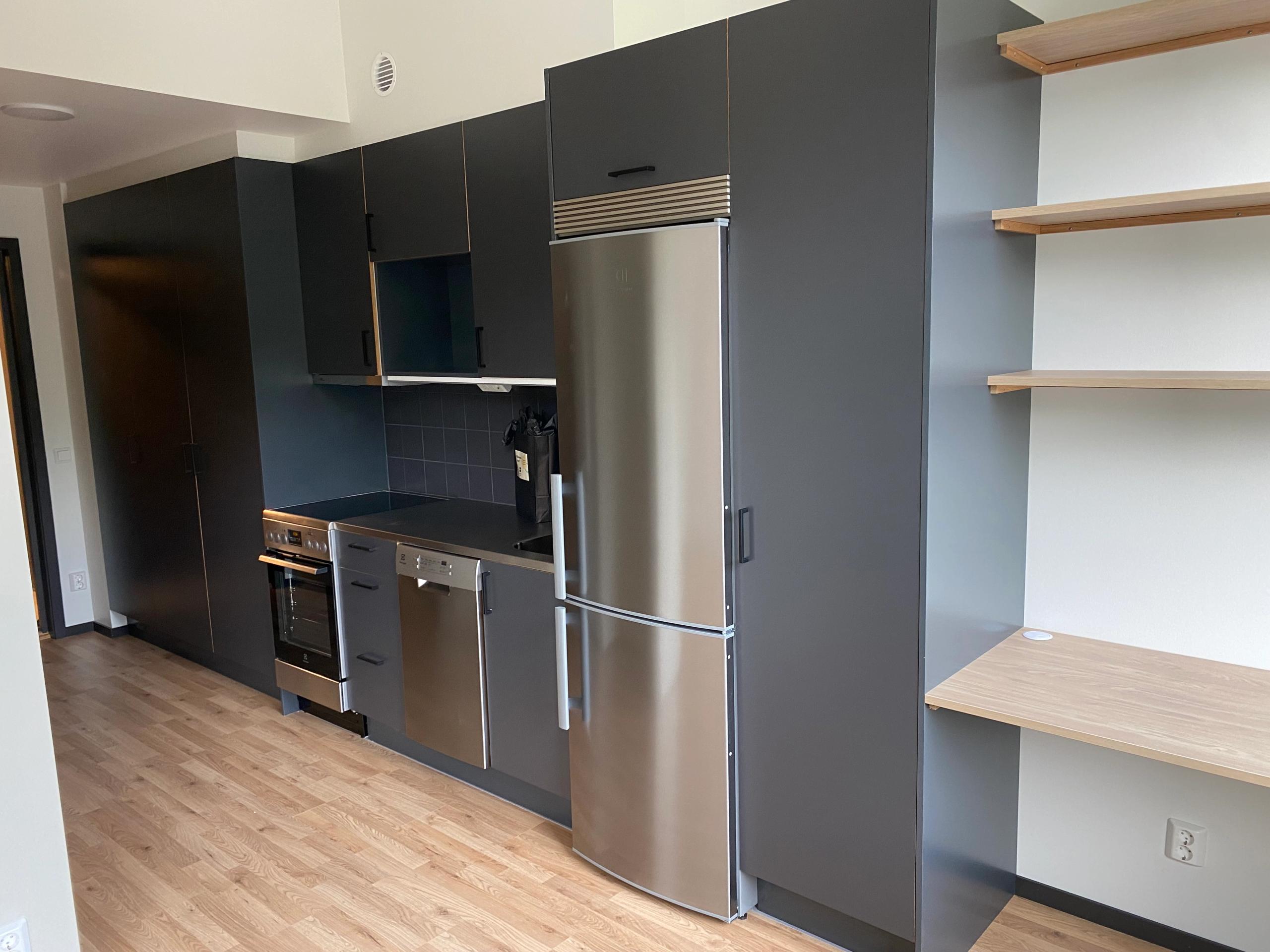 A kitchen with a stainless steel fridge and a wooden floor.