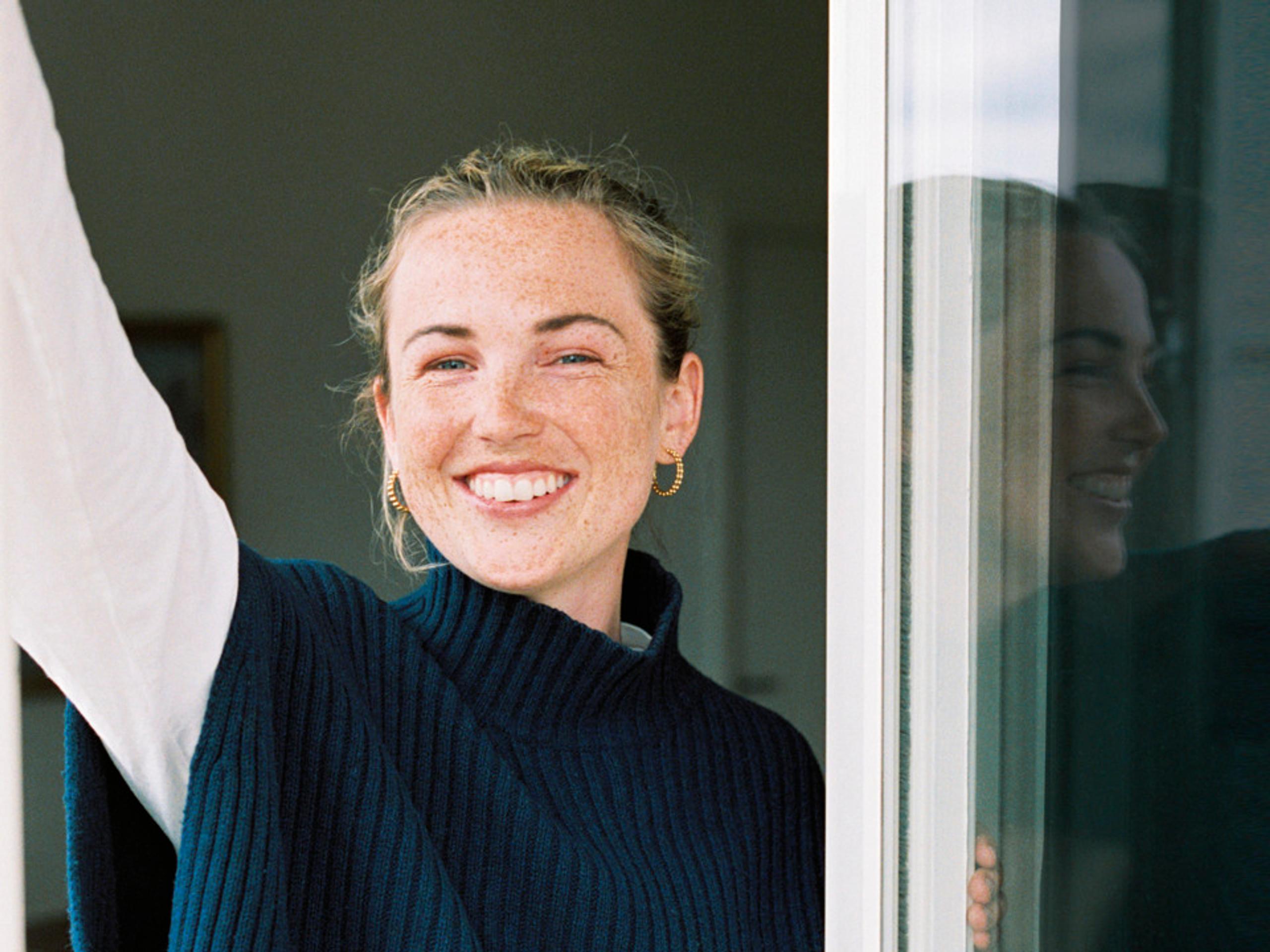 A young woman smiling at the viewer in a window