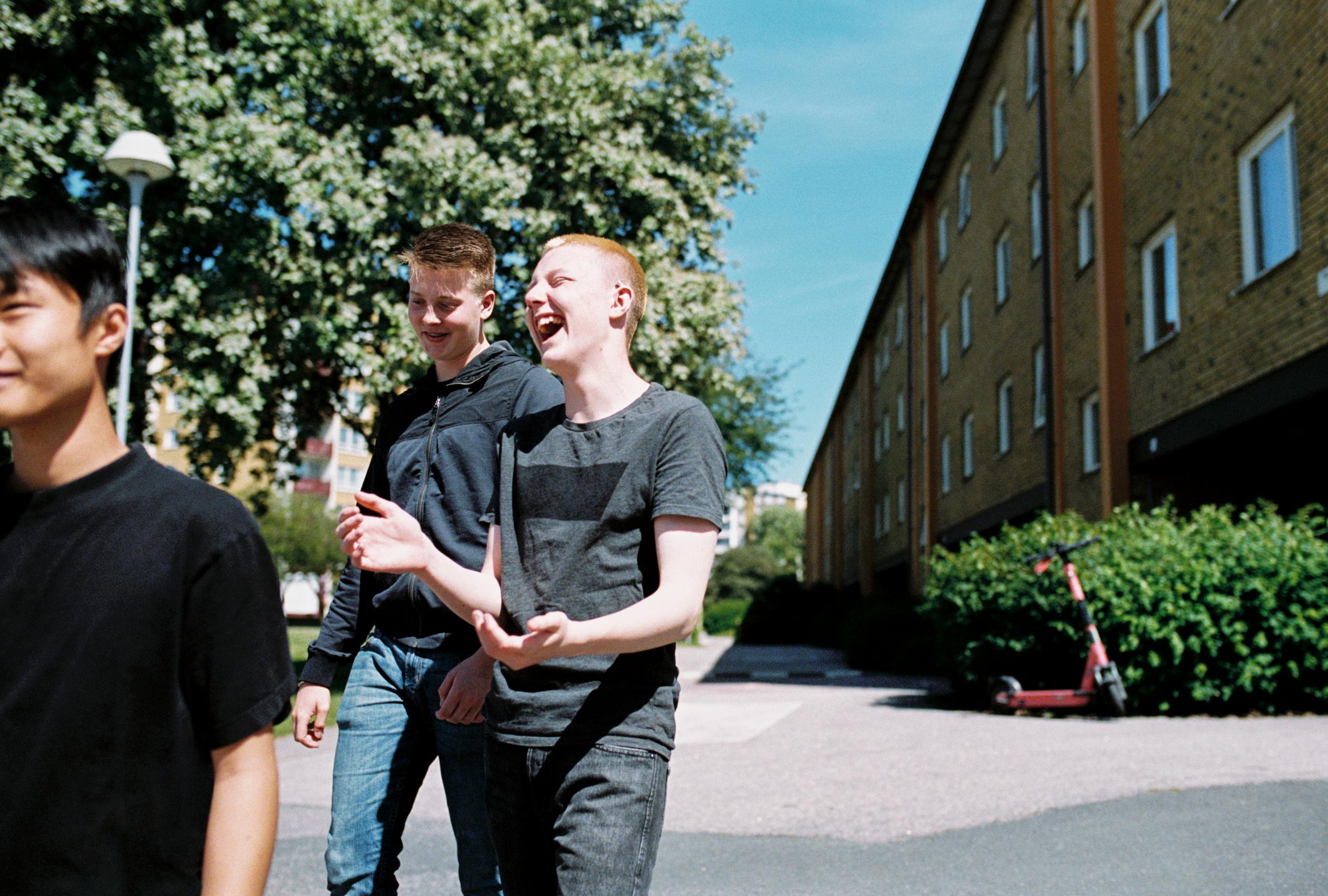 Three cheerful young men walking together in a residential area