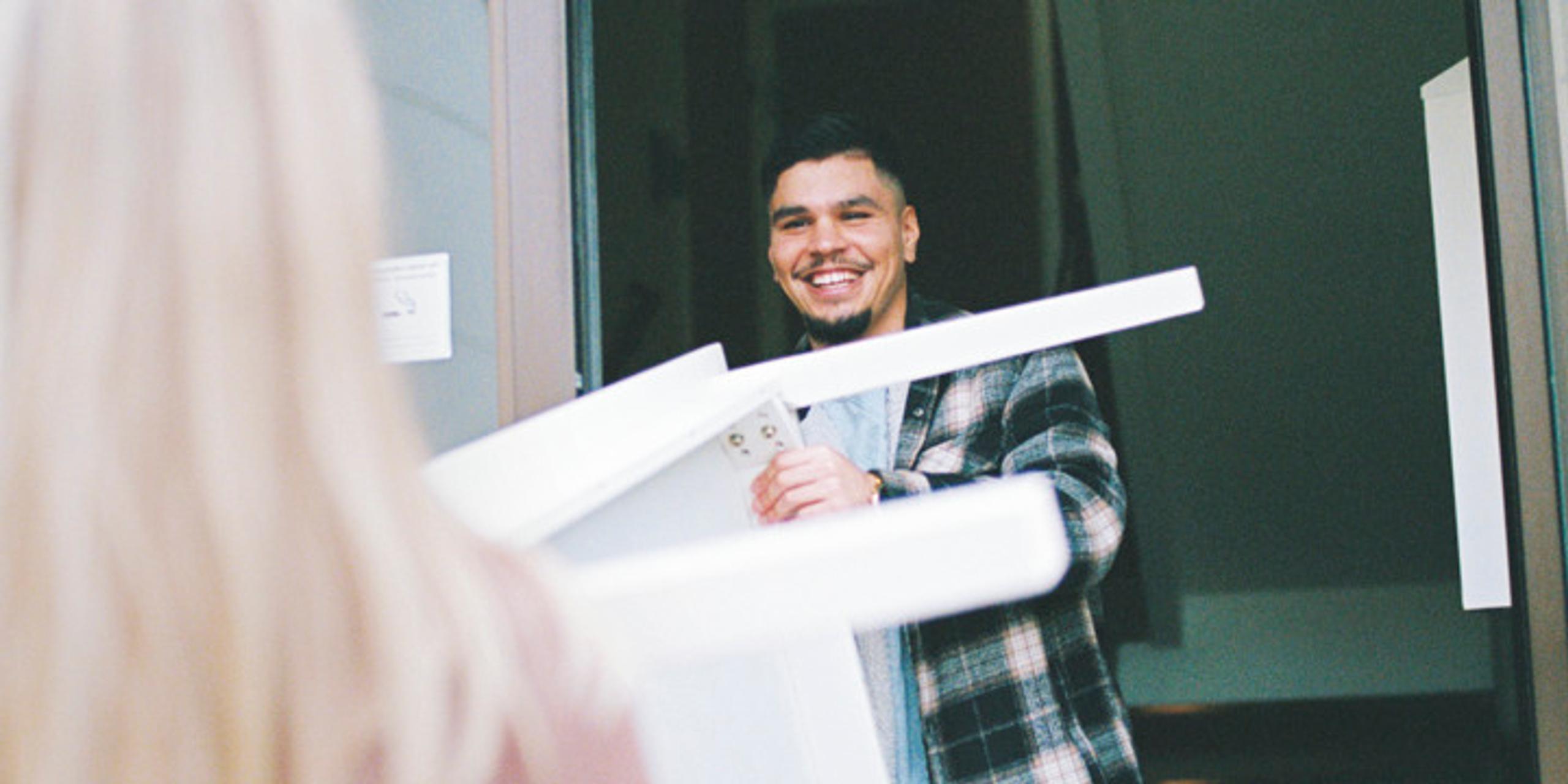 A young woman and a young man carrying a table into or out of an apartment