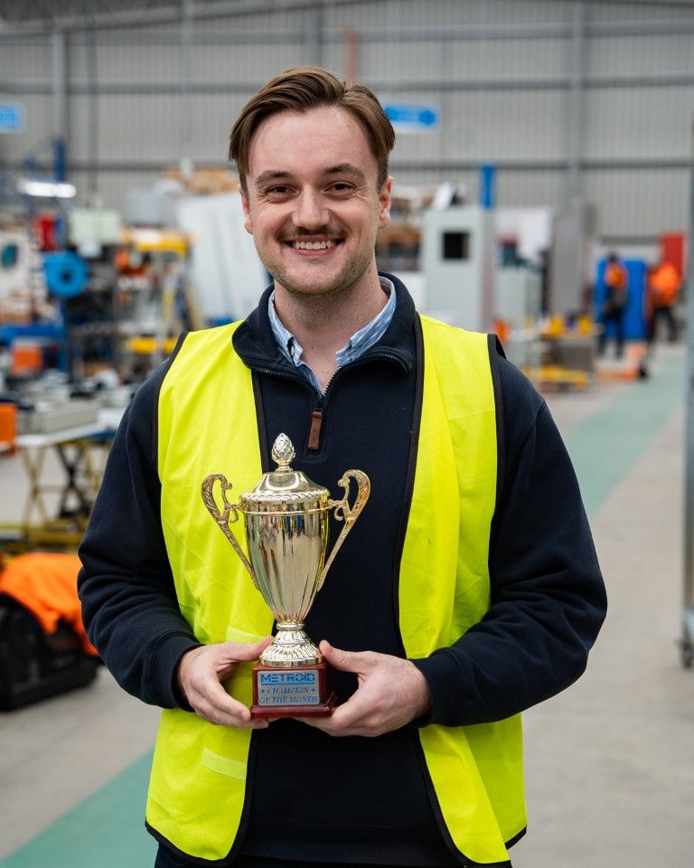 A Metroid team member with a Champion of the Month trophy
