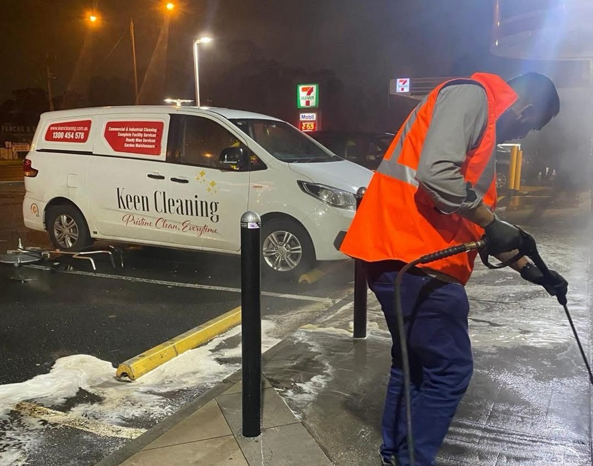 After-hours pressure washing of a commercial forecourt next to a Keen Cleaning van
