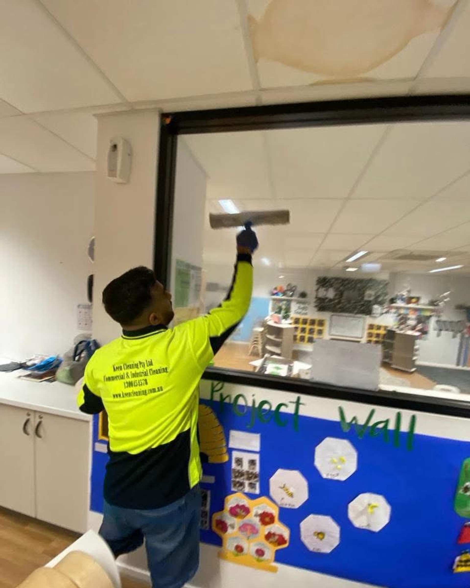 Keen Cleaning technician cleaning interior glass in a childcare classroom