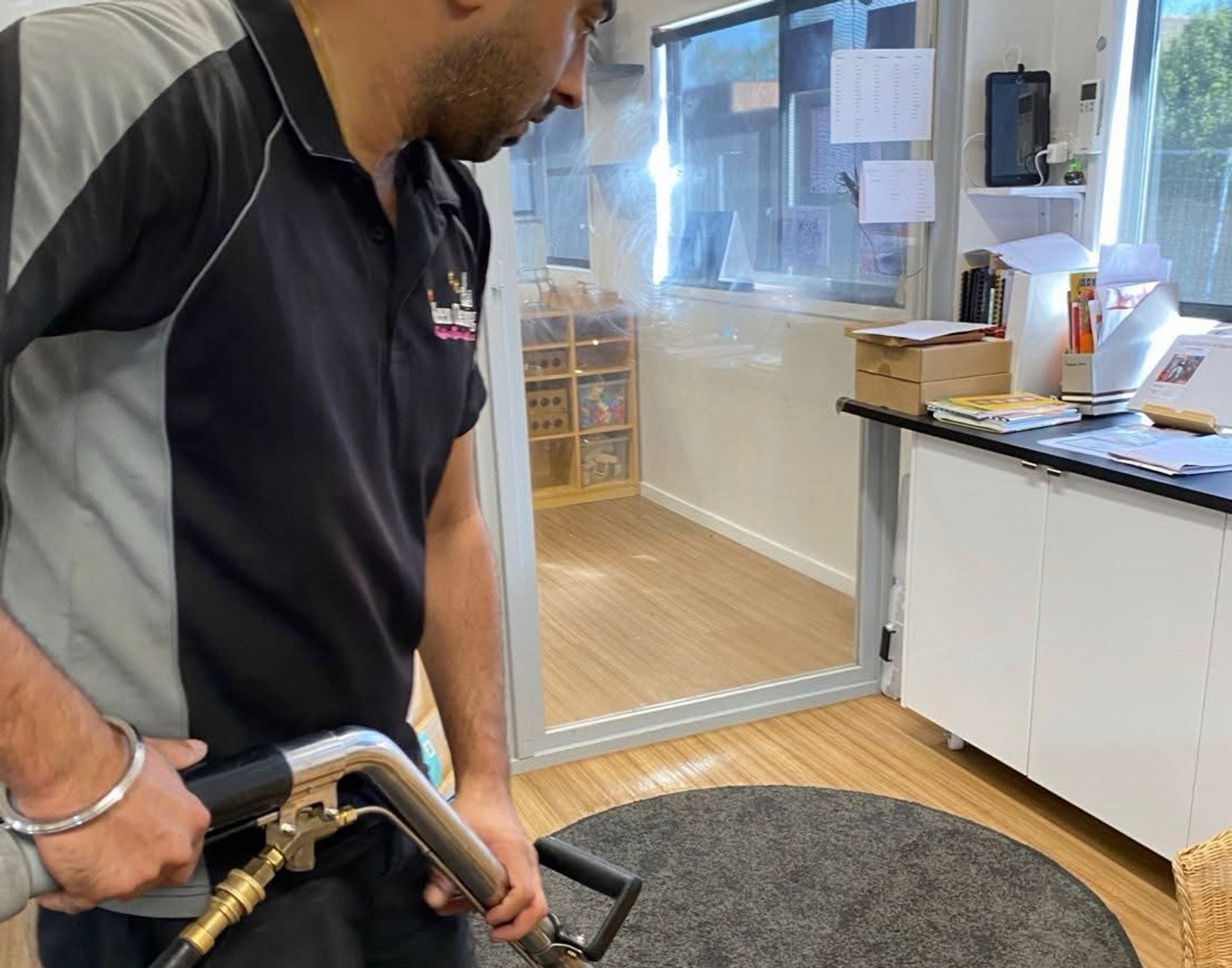 Technician steam-cleaning a rug with a professional carpet wand