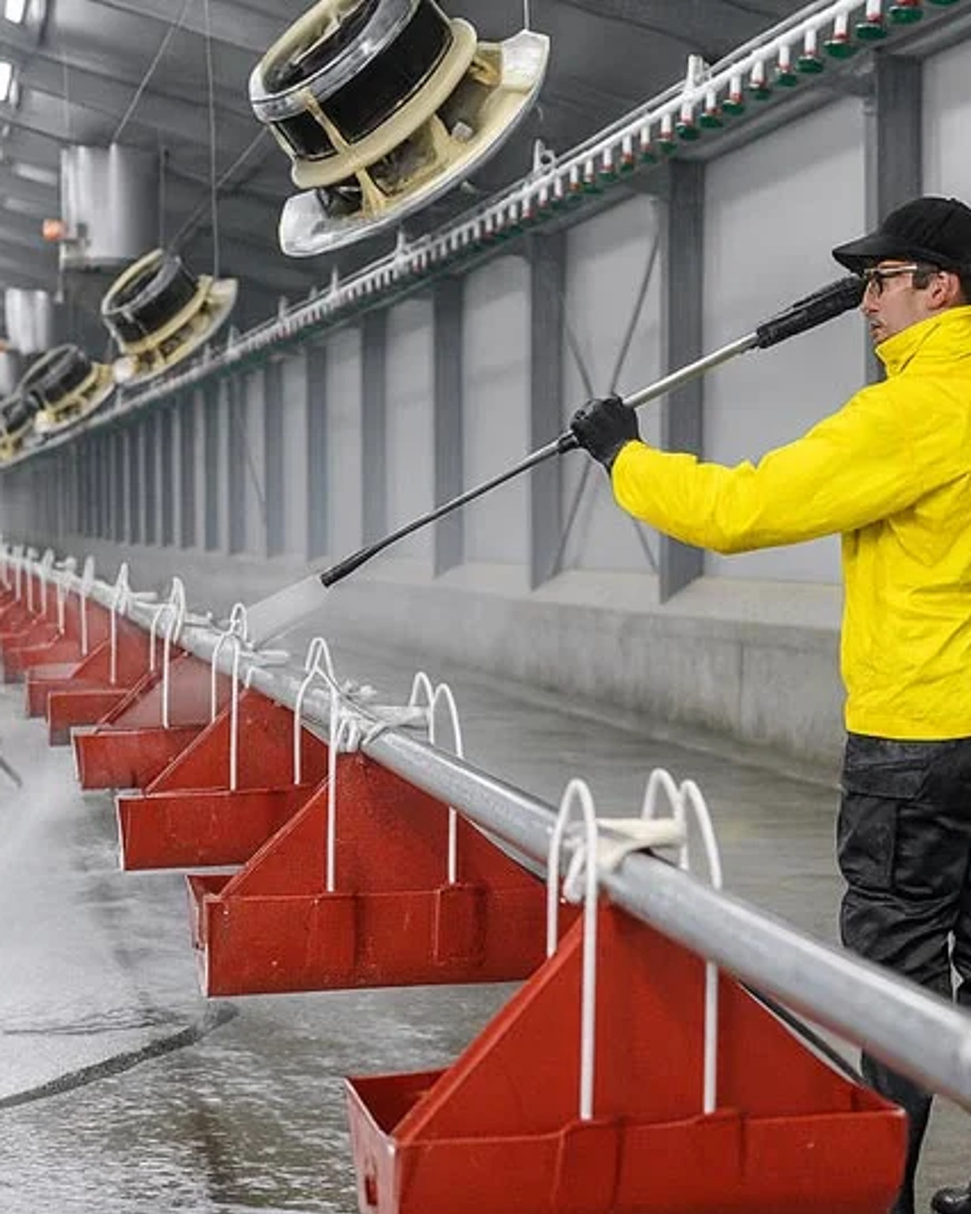 Sanitation worker in PPE deep cleaning stainless steel meat processing equipment