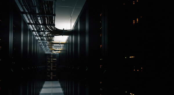 Long-exposure photograph of fibre cabling and server status lights in a data centre — automation infrastructure