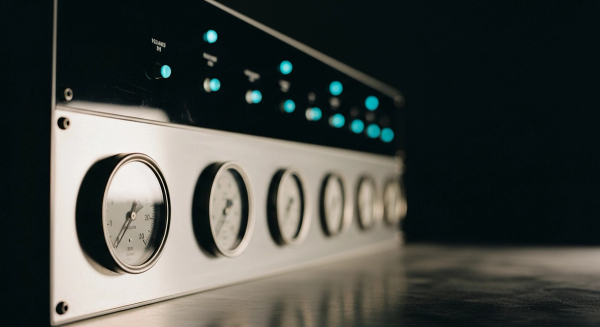 LLM benchmarking hero — a row of precision analog measurement gauges on a dark lab control panel