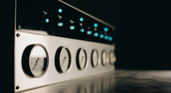 LLM benchmarking hero — a row of precision analog measurement gauges on a dark lab control panel