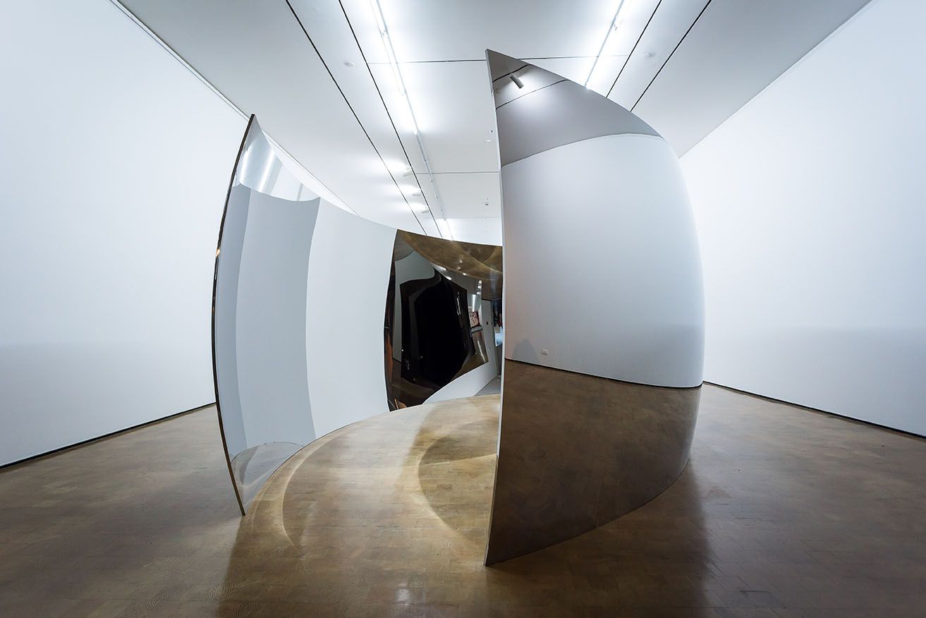 Instalación de superficies curvas metálicas en una sala de exposición.