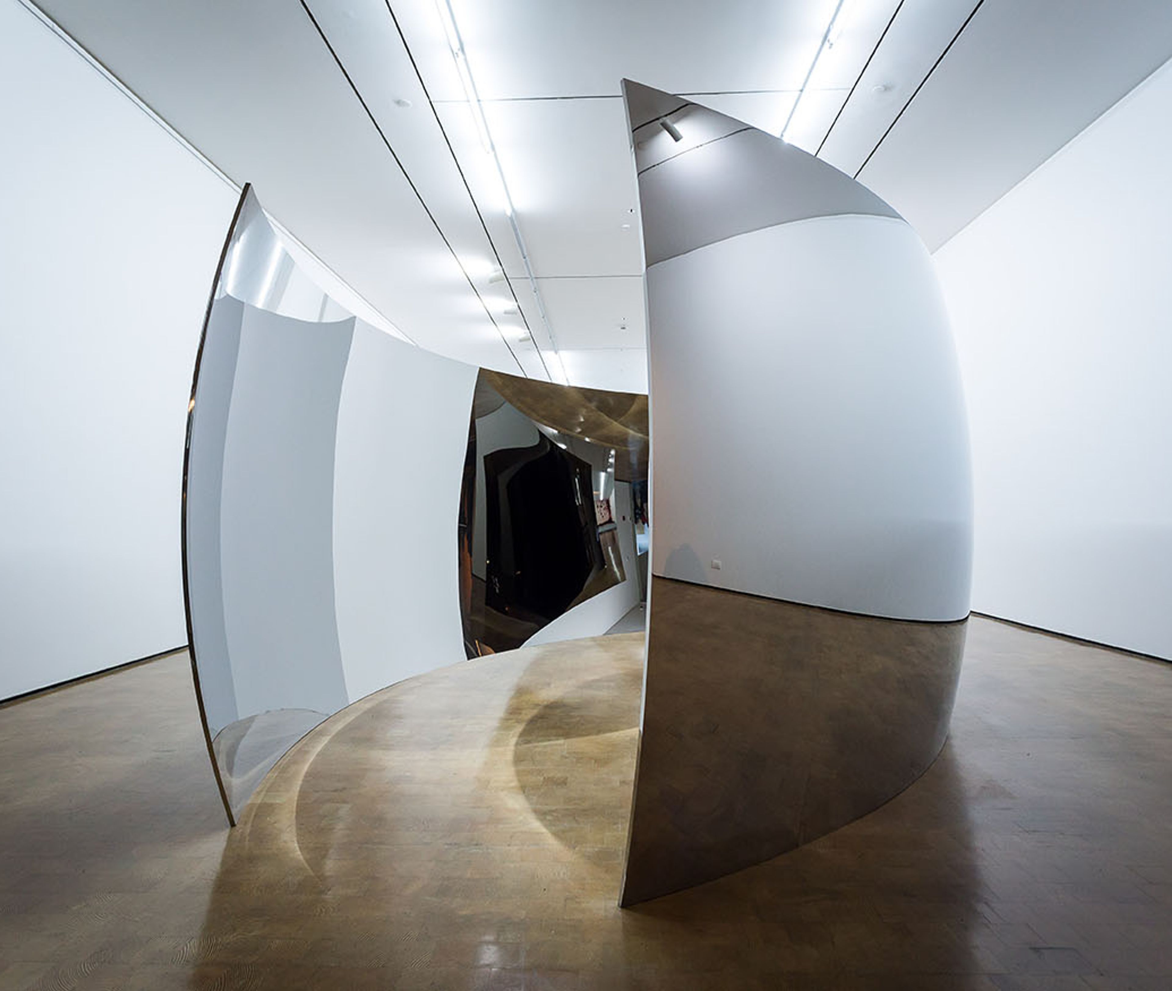 Instalación de superficies curvas metálicas en una sala de exposición.
