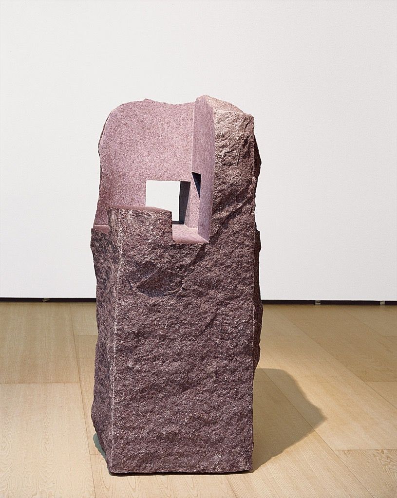 Escultura de piedra rosada con una abertura rectangular.