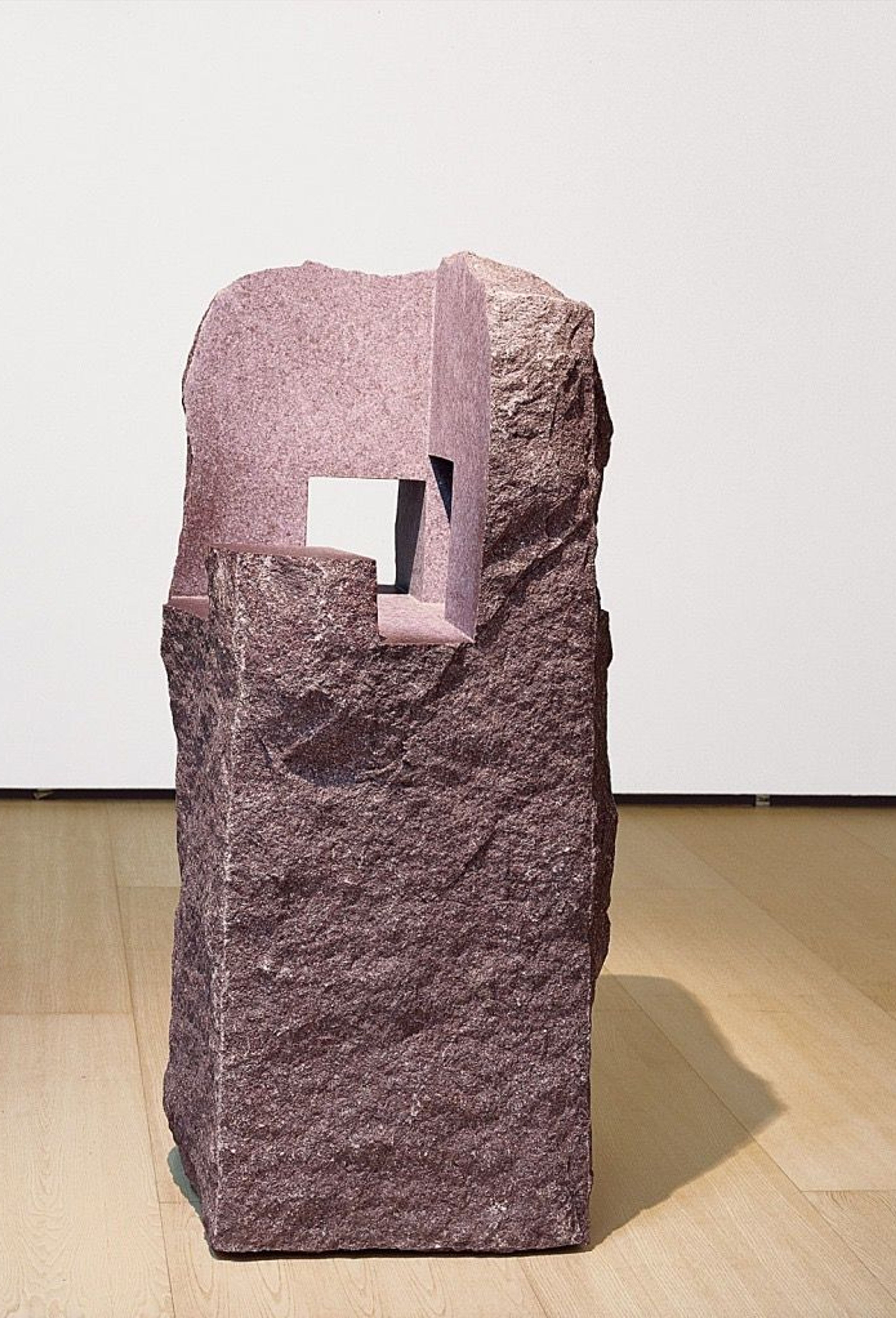 Escultura de piedra rosada con una abertura rectangular.