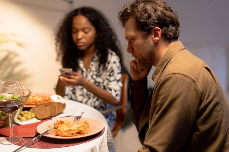 couple at dinner table looking sad and disconnected
