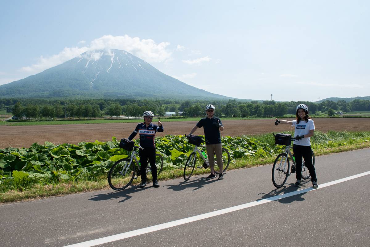 Cyclists on a guided tour pose in front of a volcano