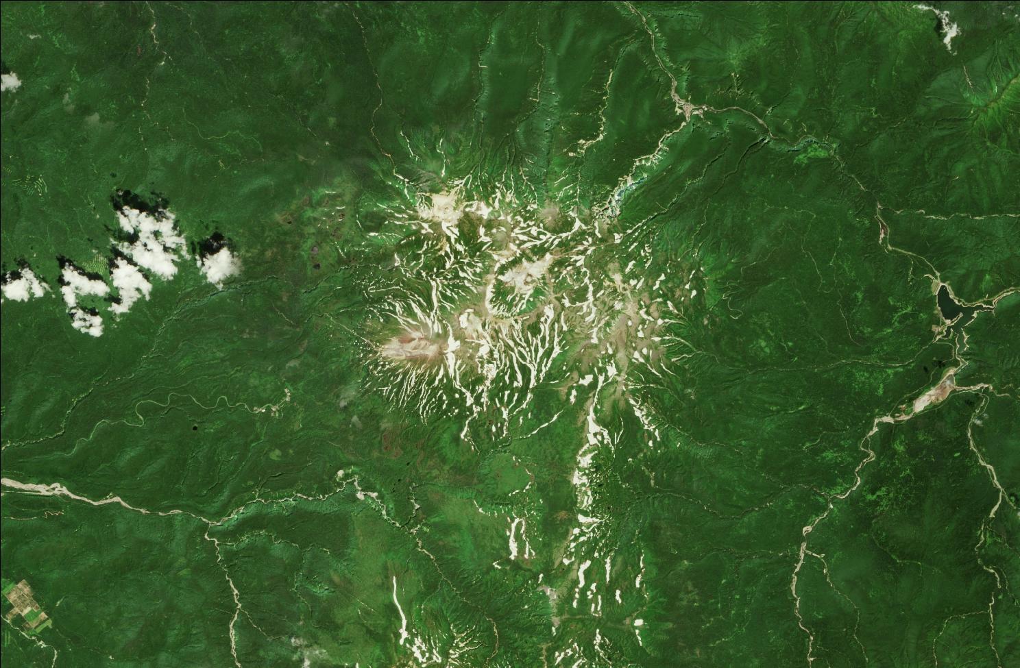 A satellite image showing snow over the northern Daisetsuzan mountains. Strips of snow remain in the mountains while the rest of the landscape is green.