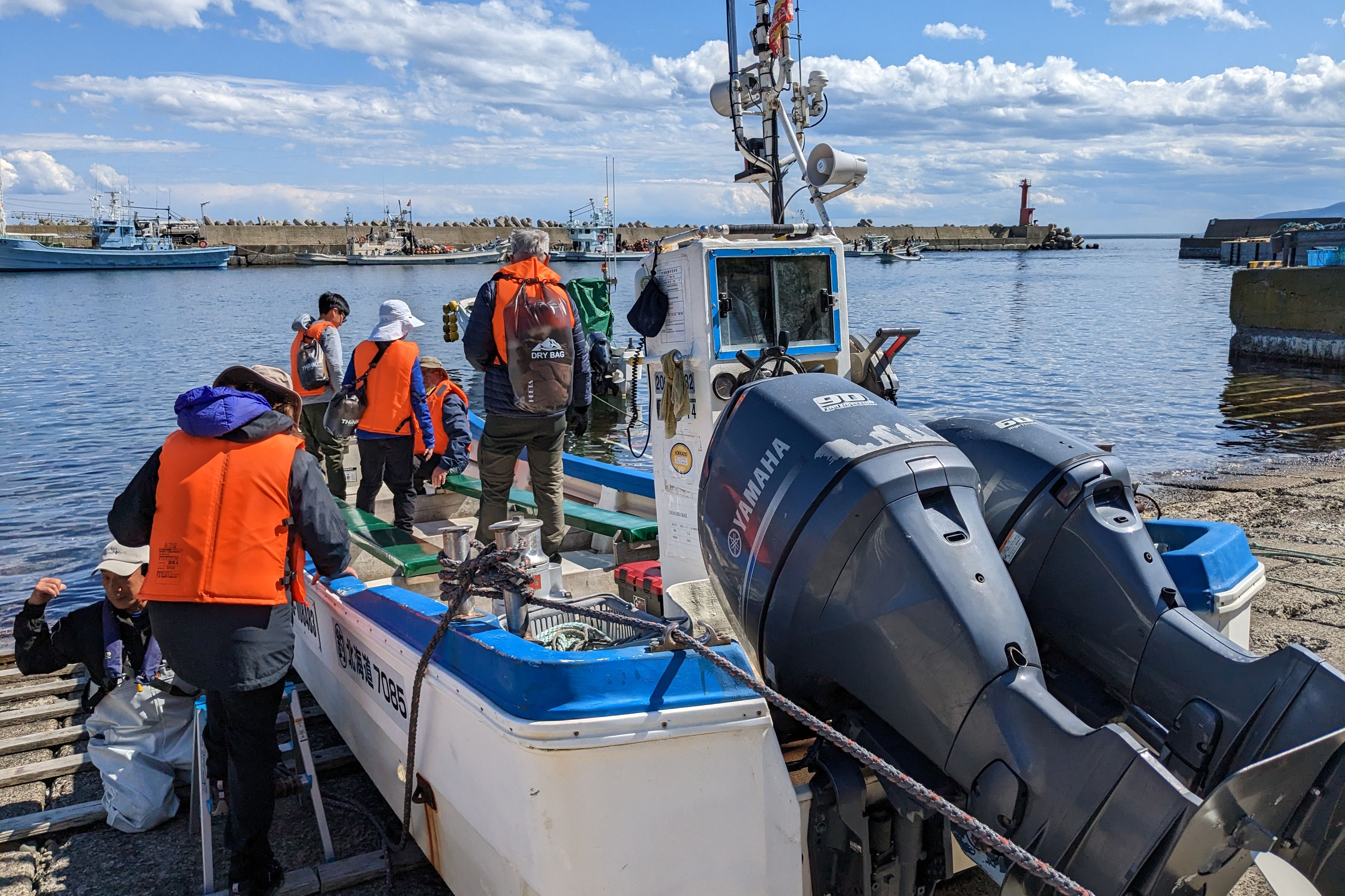 A group of tourists board a small boat in a fishing harbour near Rausu Shiretoko