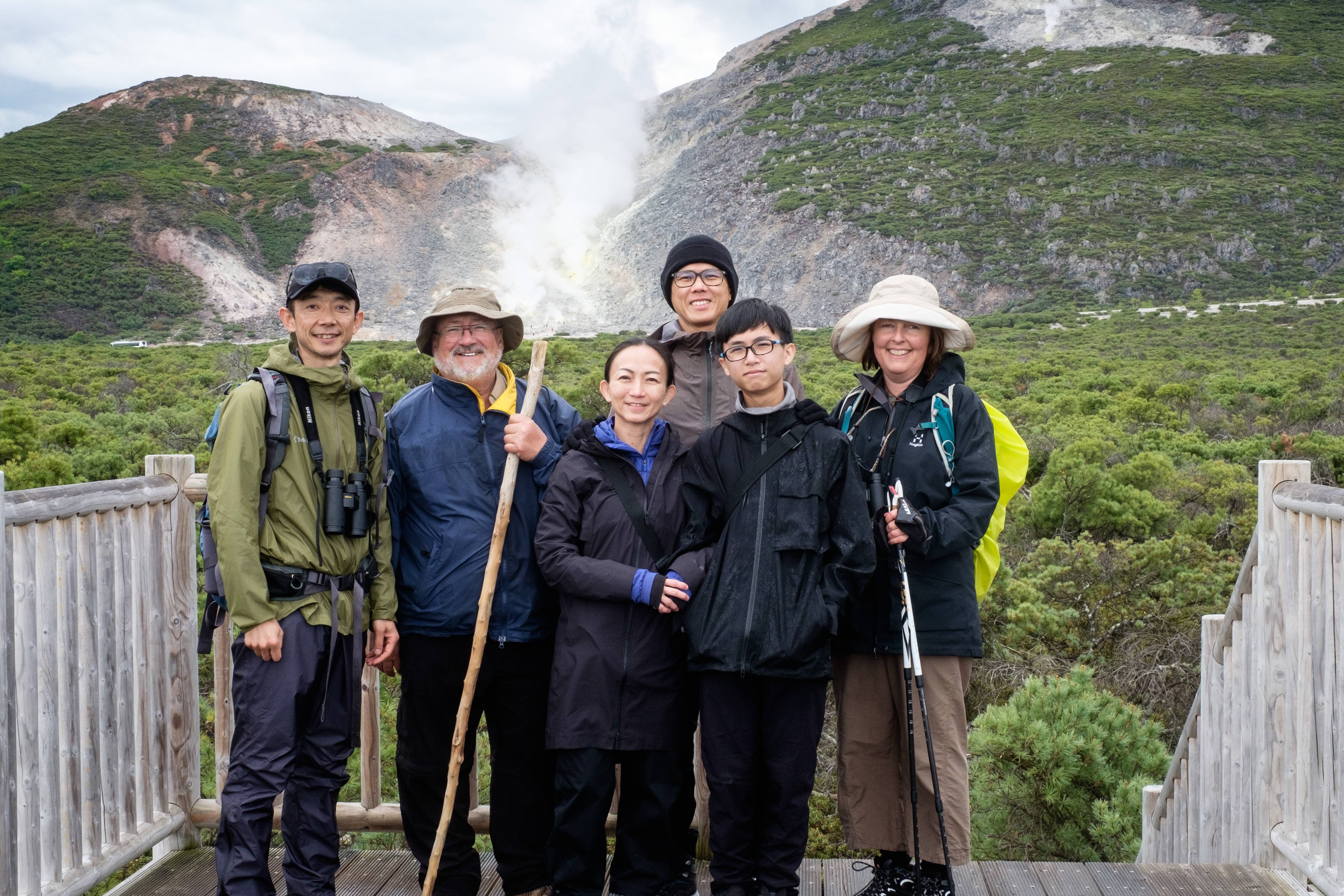 A group of walkers pose in front of Mt Io. In the background the sulphuric steam can be seen rising from an exposed patch of land.