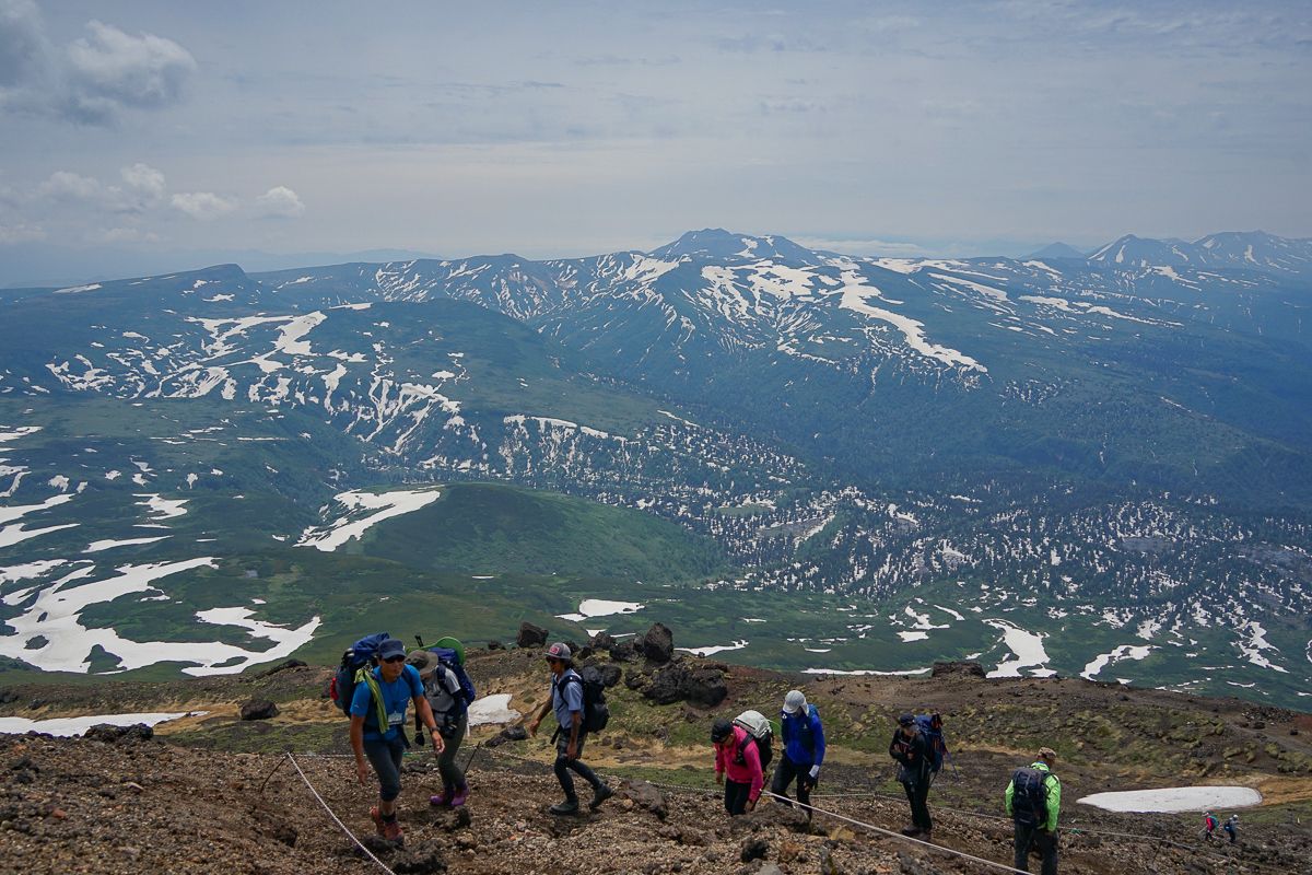 Climbing Mt Asahidake with snowpatched mountains on the backdrop