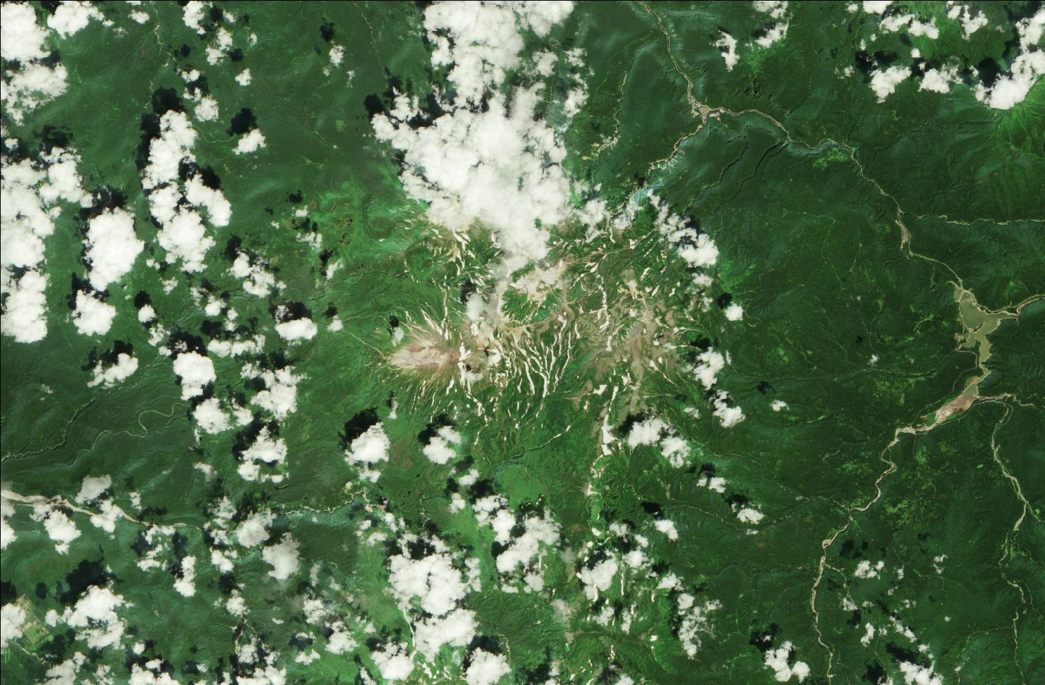 A satellite image showing snow over the northern Daisetsuzan mountains. Strips of snow remain in the mountains while the rest of the landscape is green. Clouds are dotted across the image.