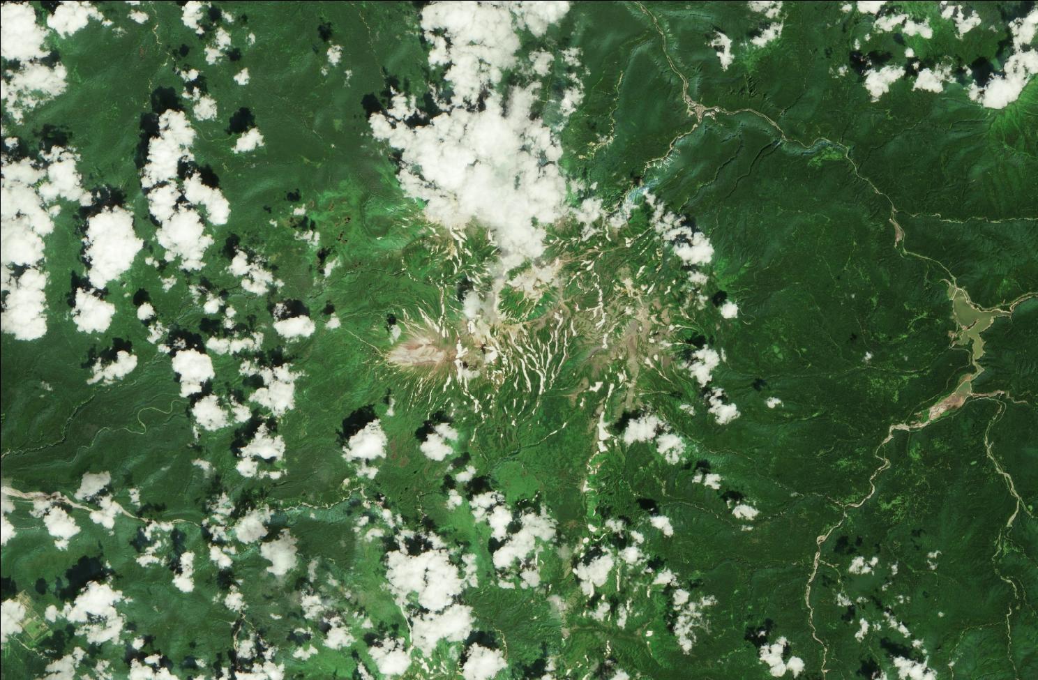 A satellite image showing snow over the northern Daisetsuzan mountains. Strips of snow remain in the mountains while the rest of the landscape is green. Clouds are dotted across the image.