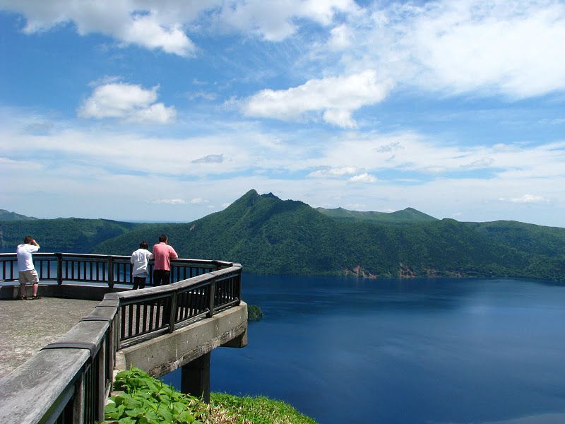 Three sightseers observe Mt. Mashu from Lake Mashu's third observation deck.