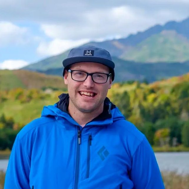 Adventure Hokkaido Guide Richard smiles to the camera while standing in front of a view of Mt Rishiri