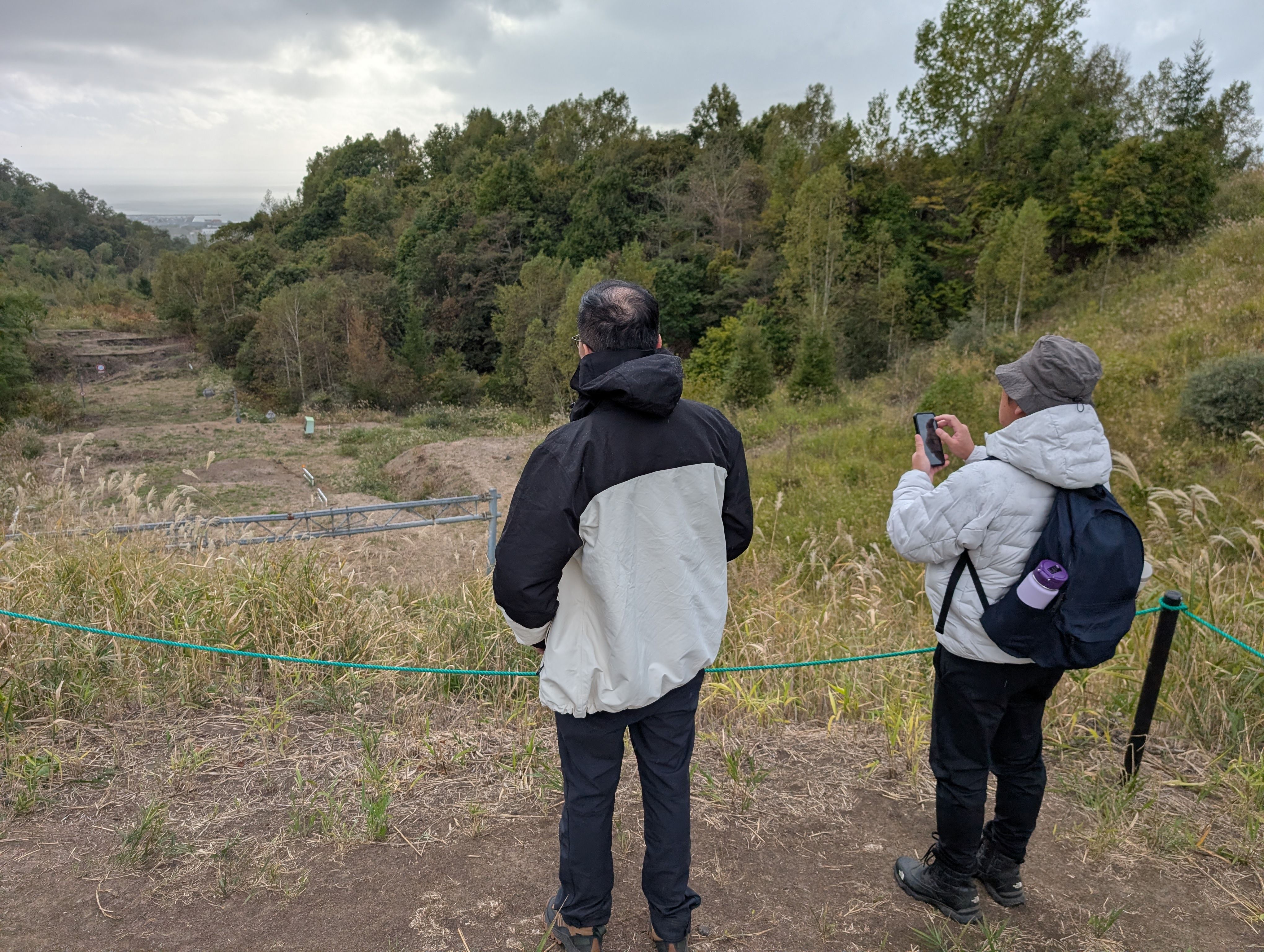 Two people look at a road forced upwards into a step-like formation by volcanic forces in 2000.
