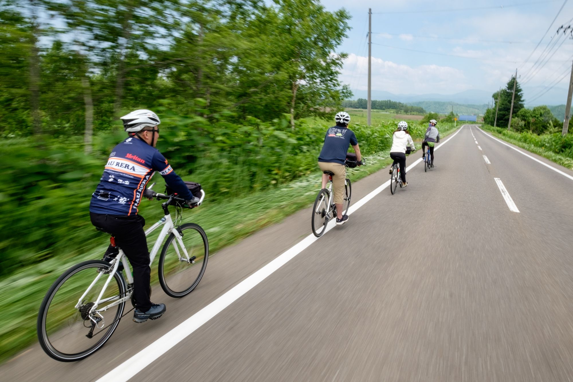 A guided cycling tour rides along a rural road surrounded by greenery.