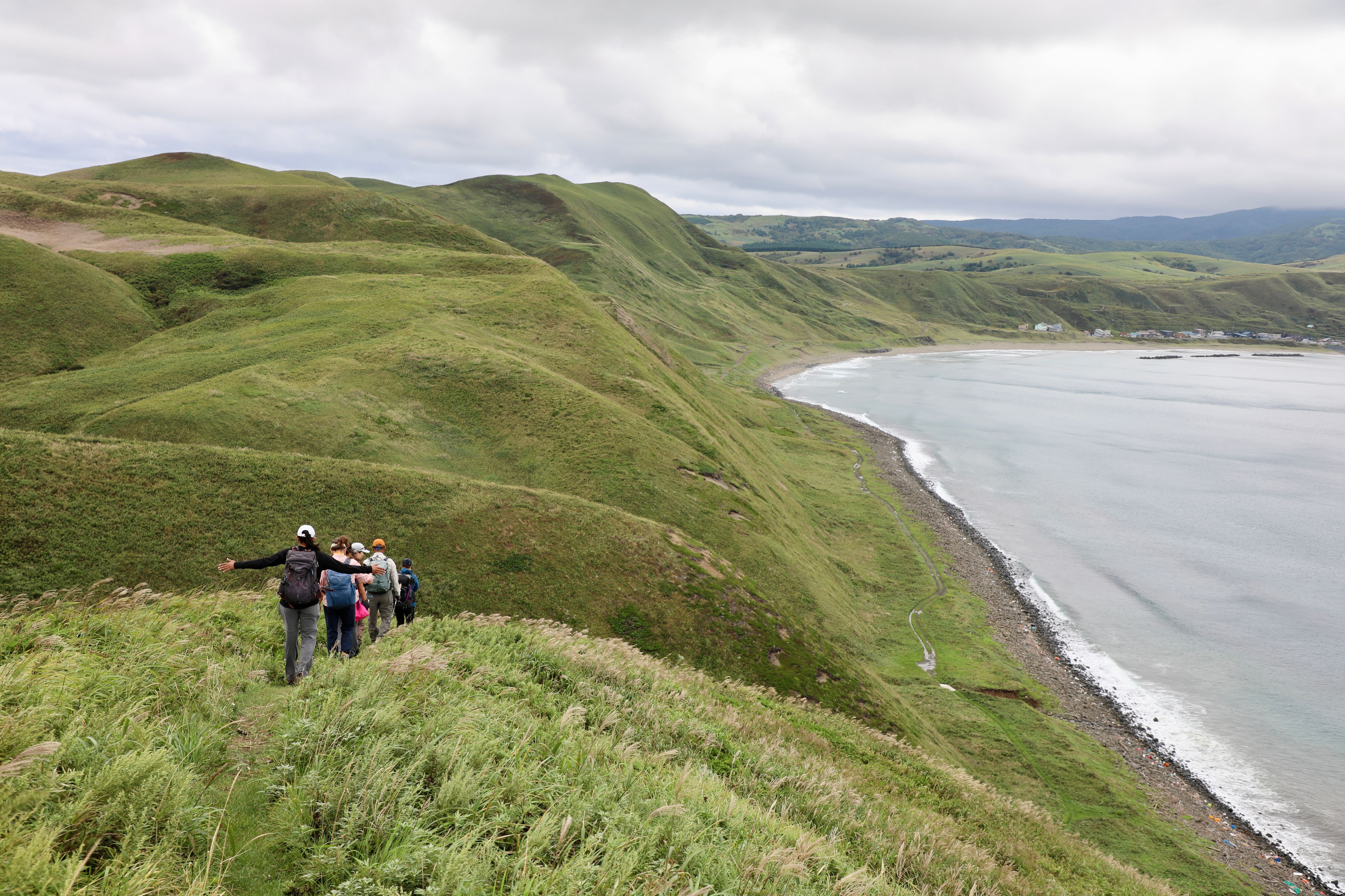 A line of hikers walk through grassland on a hilly walking trail on Rebun Island, Hokkaido. (Photo by Samir Patel)