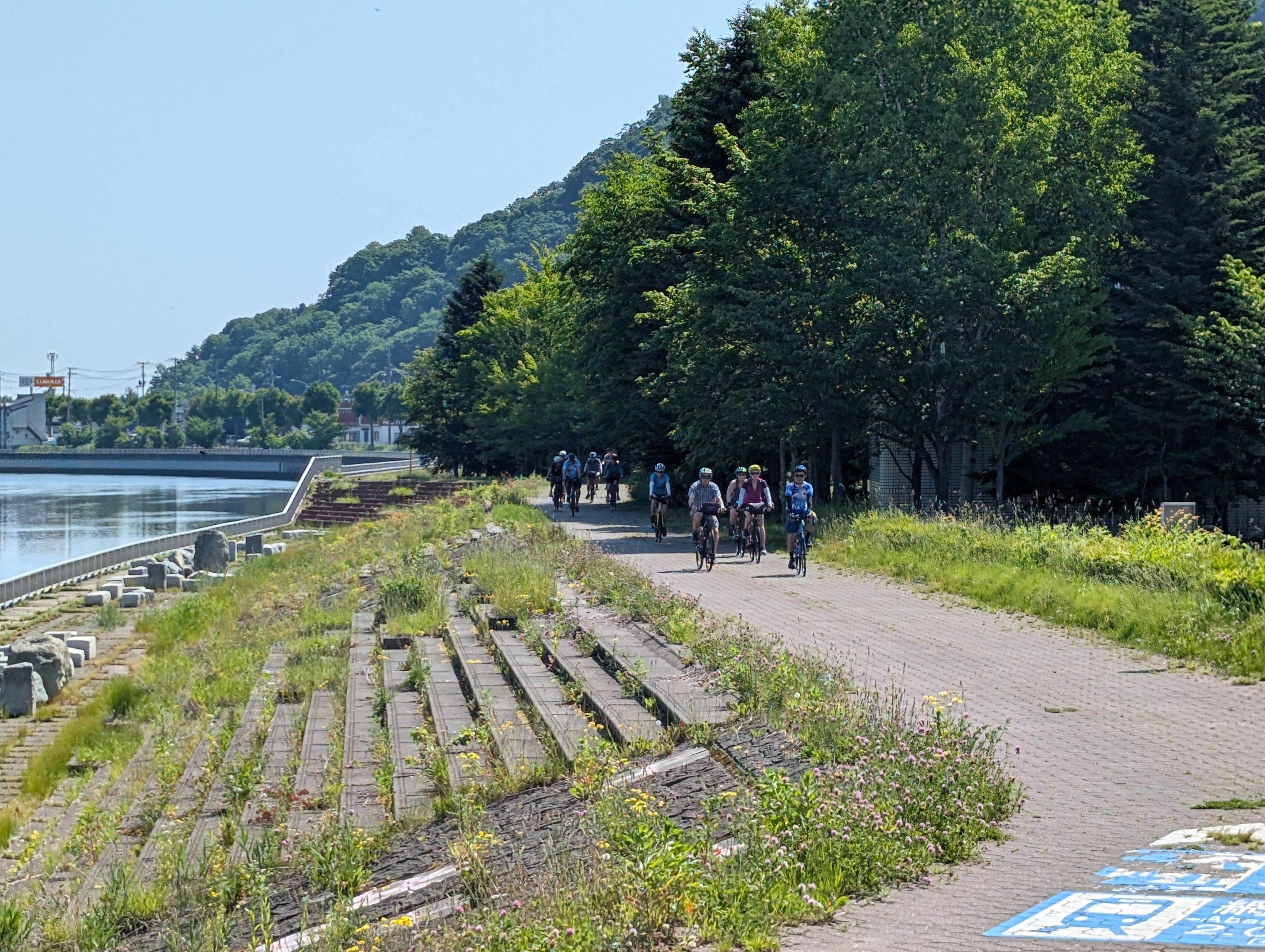 A group of cyclists ride along a cycling road next to a river in Abashiri, Hokkaido.