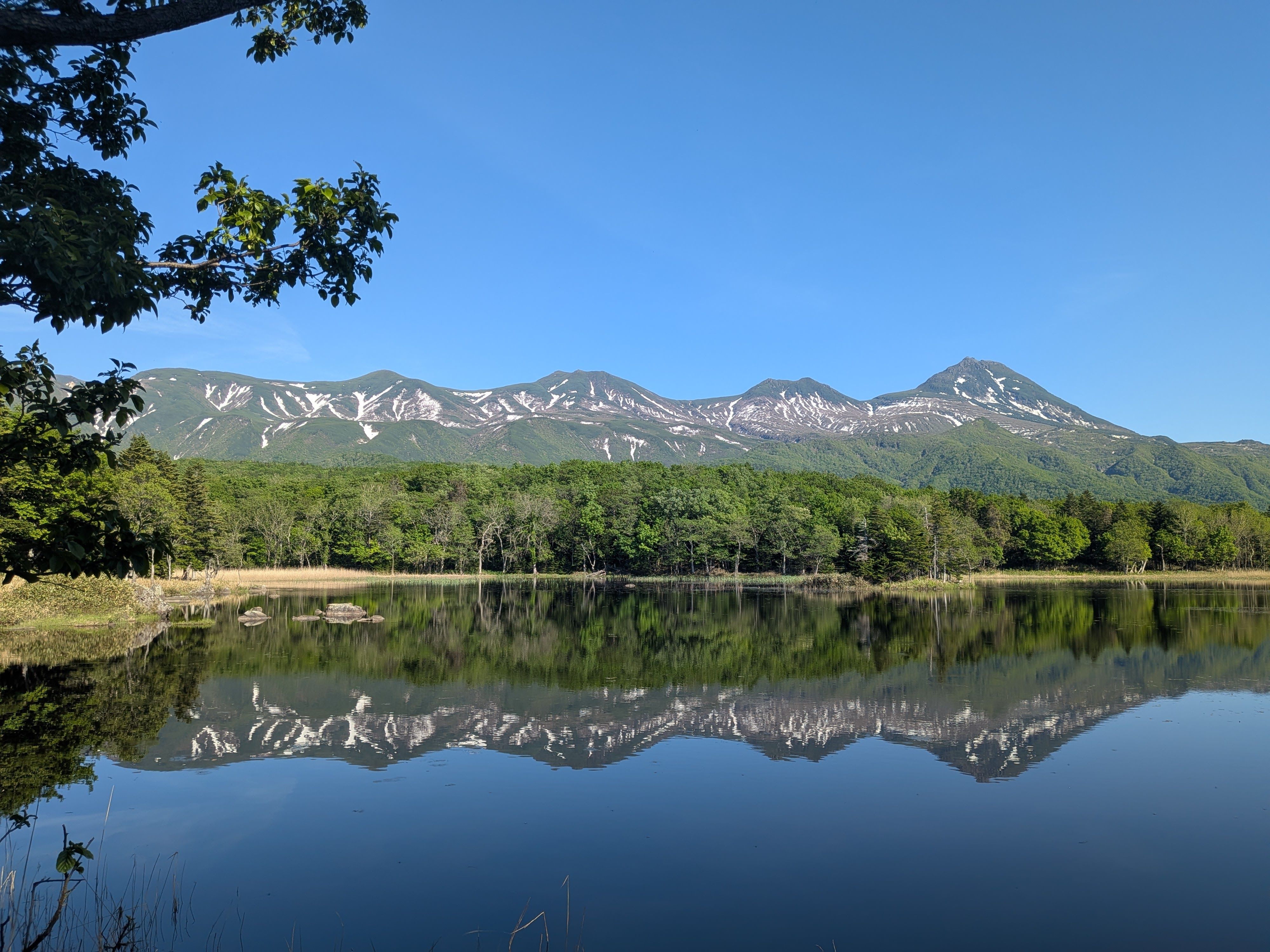A photograph of the mountains of the Shiretoko Peninsula reflected perfectly in one of the lakes of Shiretoko Five Lakes.
