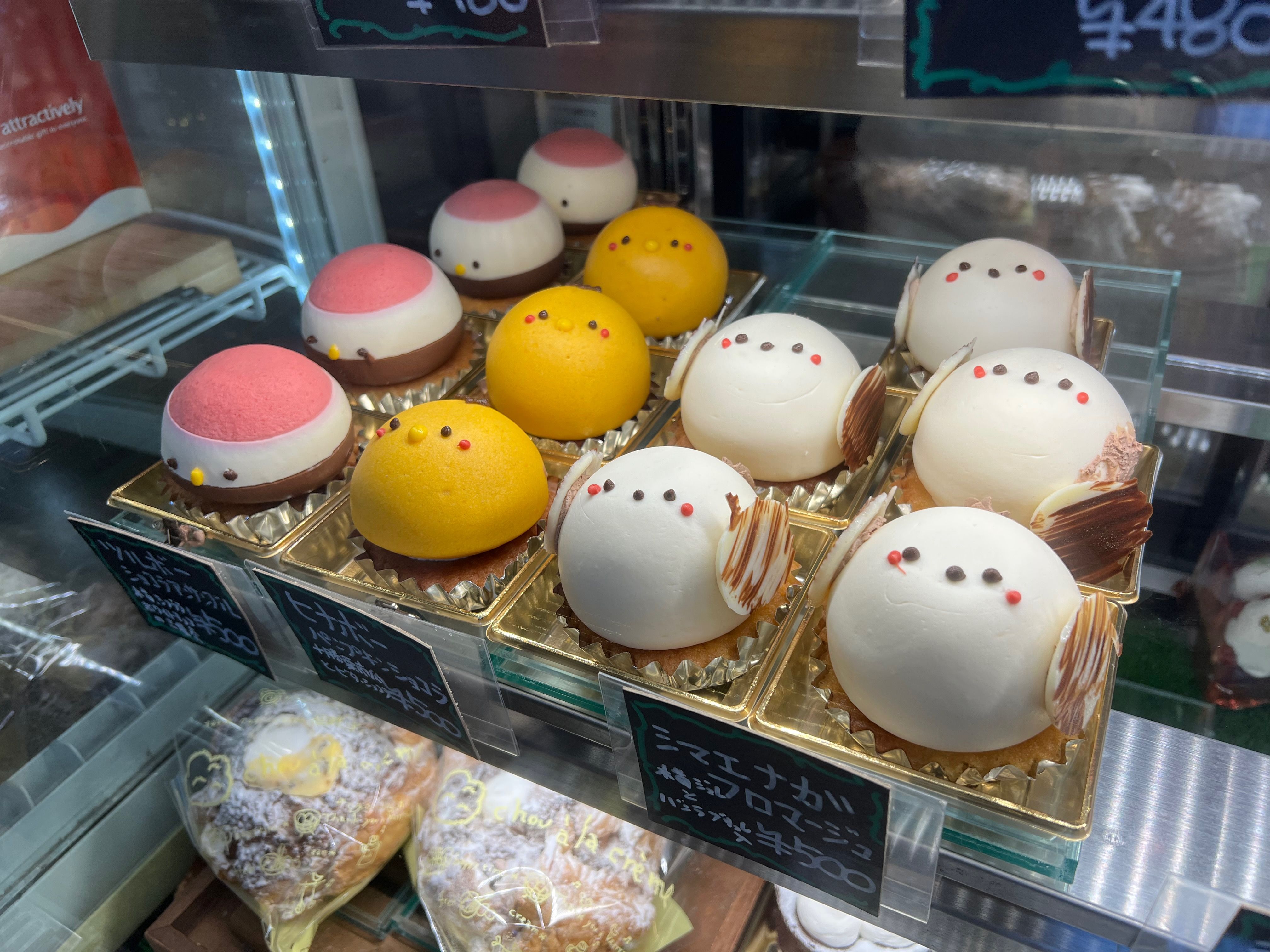 A dessert case full of round cheesecakes created to look like the birds of Hokkaido, including red-crowned cranes and long tailed tits.