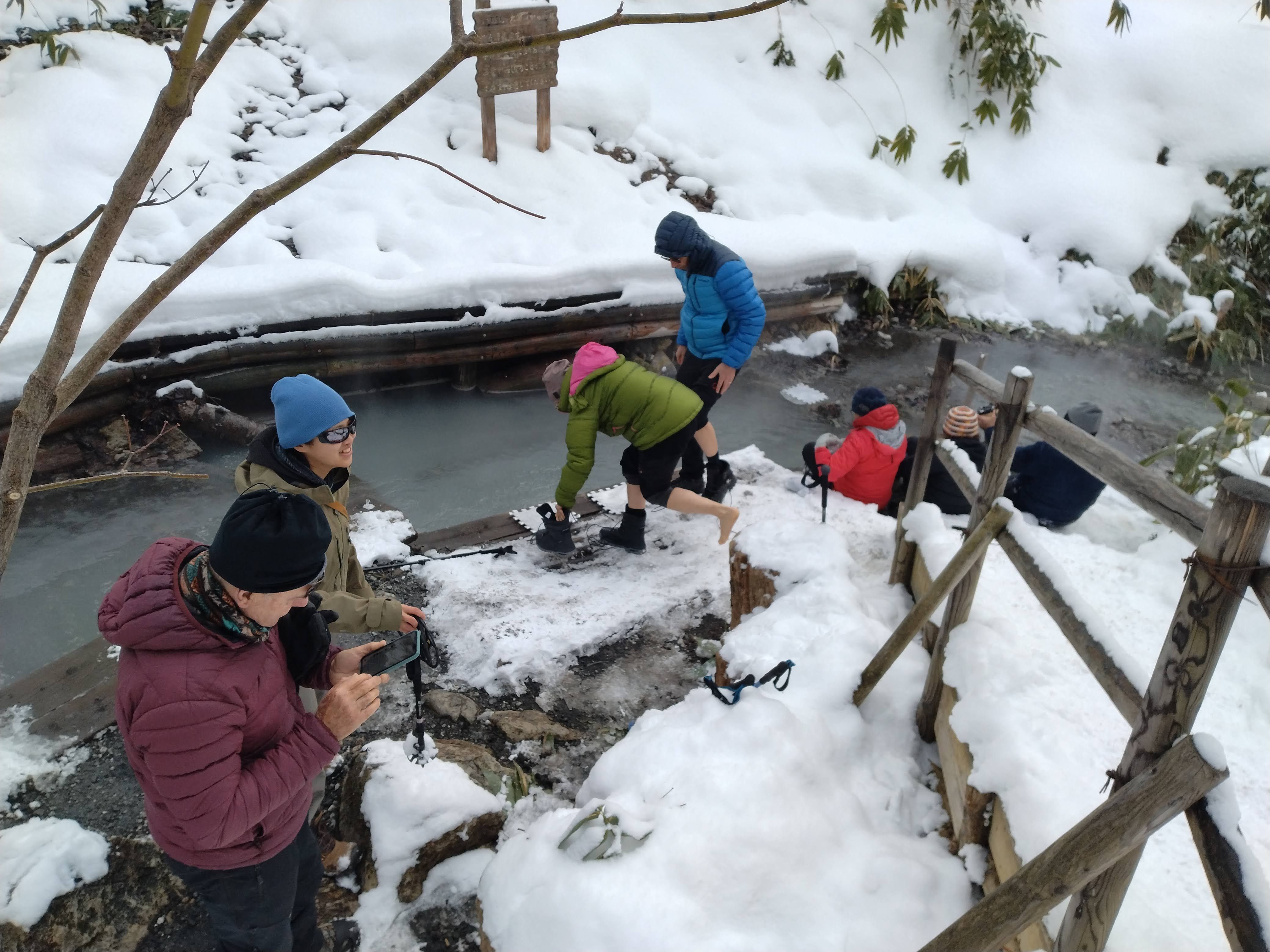 Guests huddle around a hot spring in Noboribetsu Onsen, Hokkaido, dipping their feet into it to warm up on a snowy day.