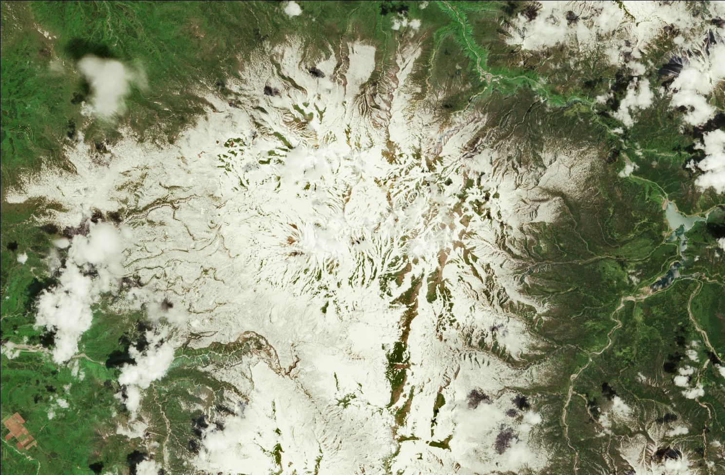 A satellite image showing snow over the northern Daisetsuzan mountains. Strips of snow remain in the mountains while the rest of the landscape is green.