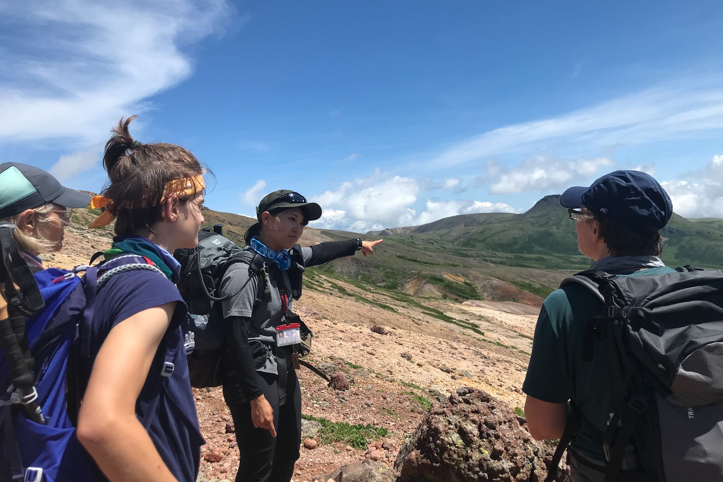 Yuka, an Adventure Hokkaido guide, points out mountains in the distance to three guests.