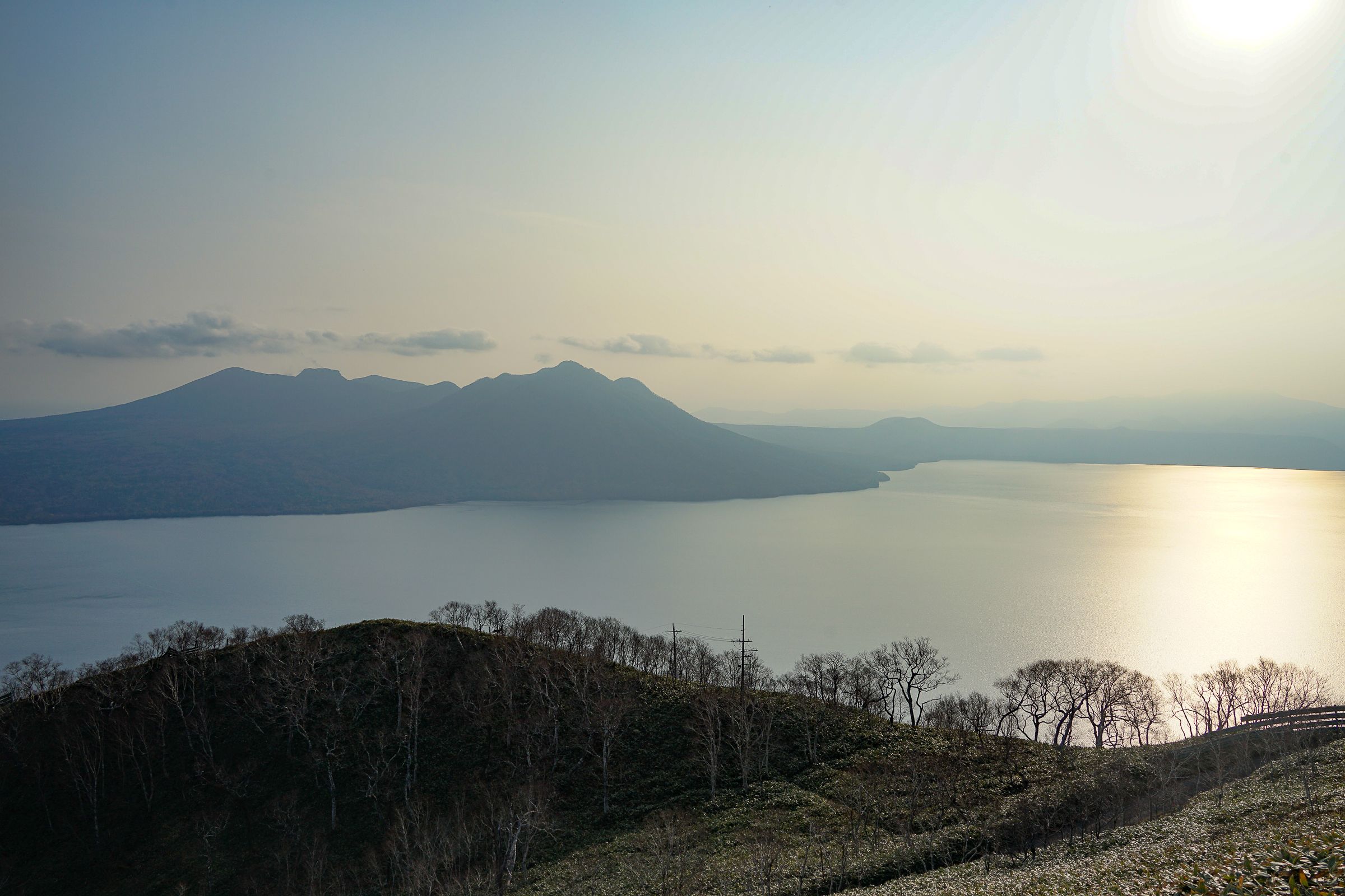 Sunlight gleams off the surface of Lake Shikotsu in autumn.