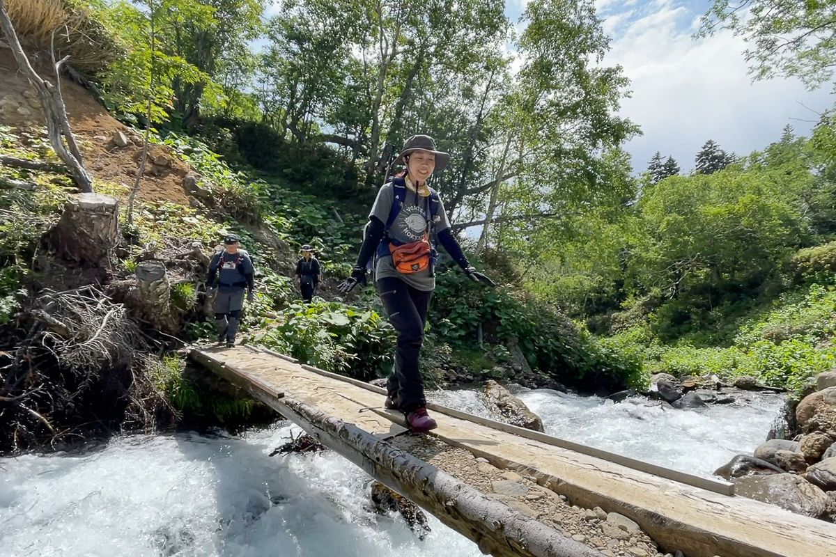 Hiker crossing a river in Daisetsuzan National Park, Hokkaido