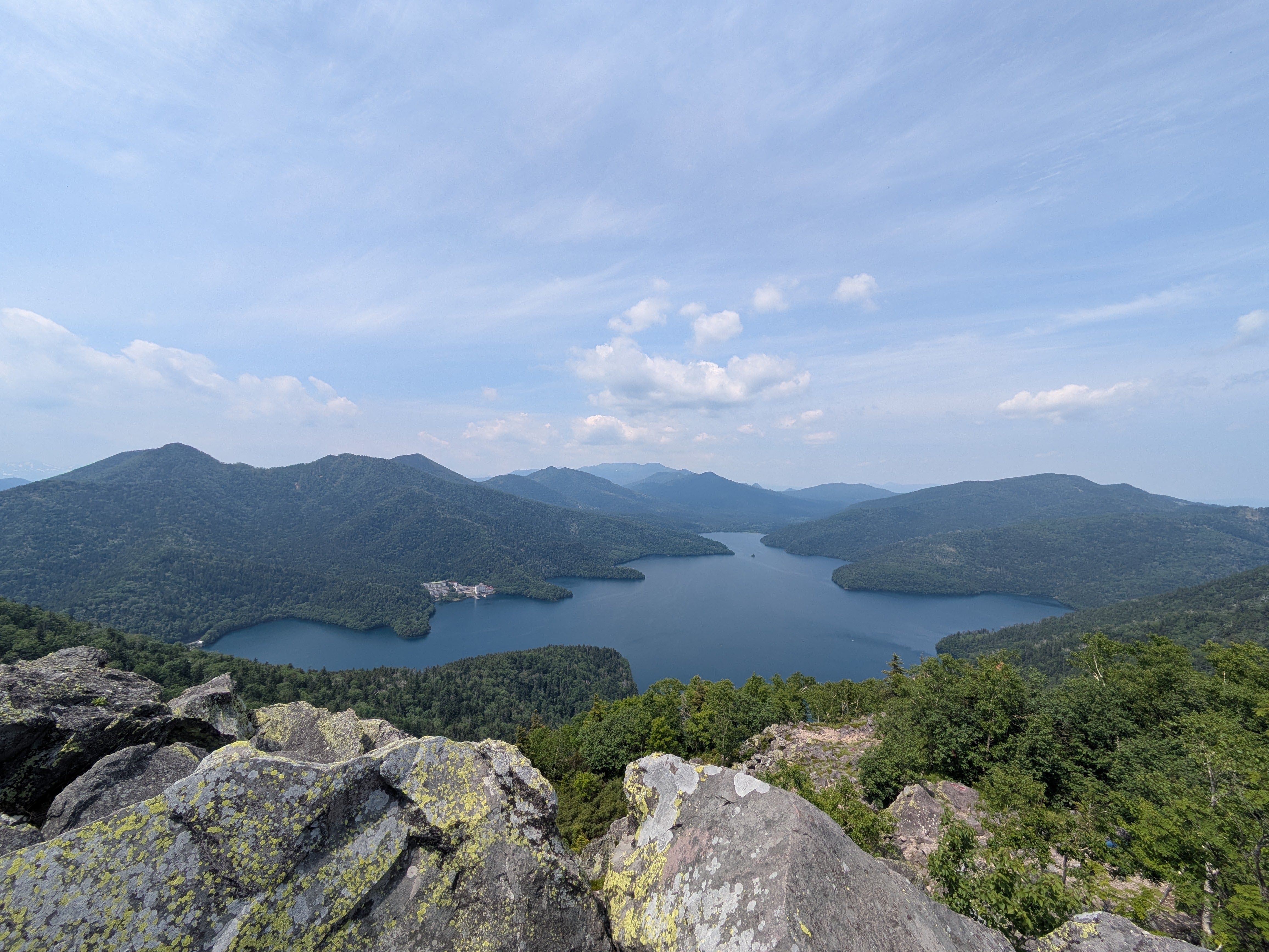 A beautiful view of Lake Shikaribetsu from the summit of Mt. Hakuundake, Hokkaido. It is a sunny day and the lake is perfectly reflecting the blue sky.